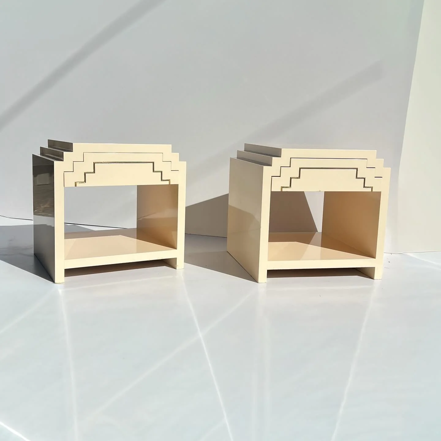 Pair of 80s Art Deco Revival bedside tables
Cream lacquer finish with striking ziggurat-style stepped detailing

Bold and sculptural &mdash; proper statement pieces.

&bull; Sold as a pair
&bull; Solid and sturdy construction

Measurements:
50cm W &t