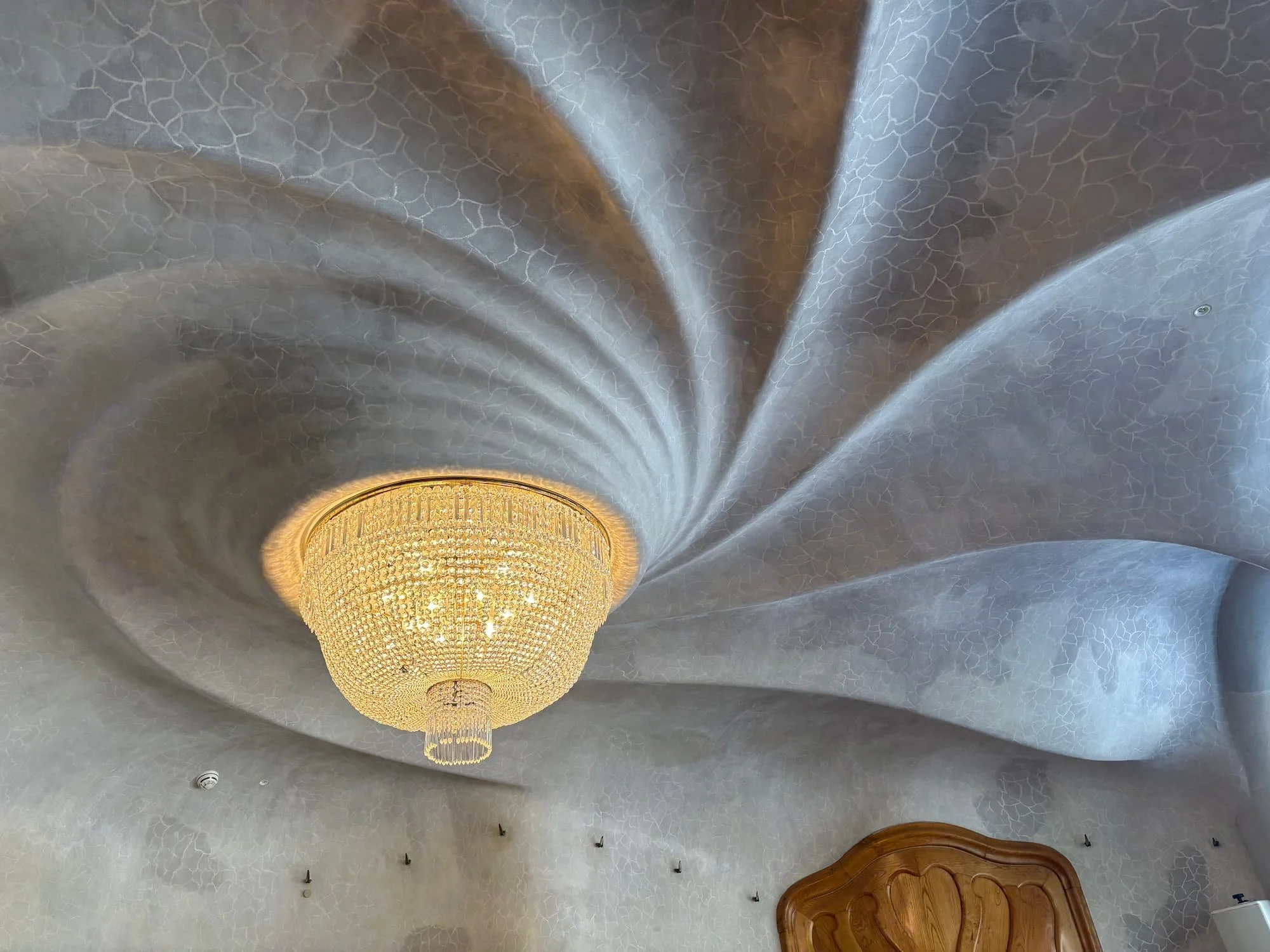 The famous swirling ceiling inside Casa Batlló's Noble Floor, featuring Gaudí's spiral design and elegant chandelier centerpiece.