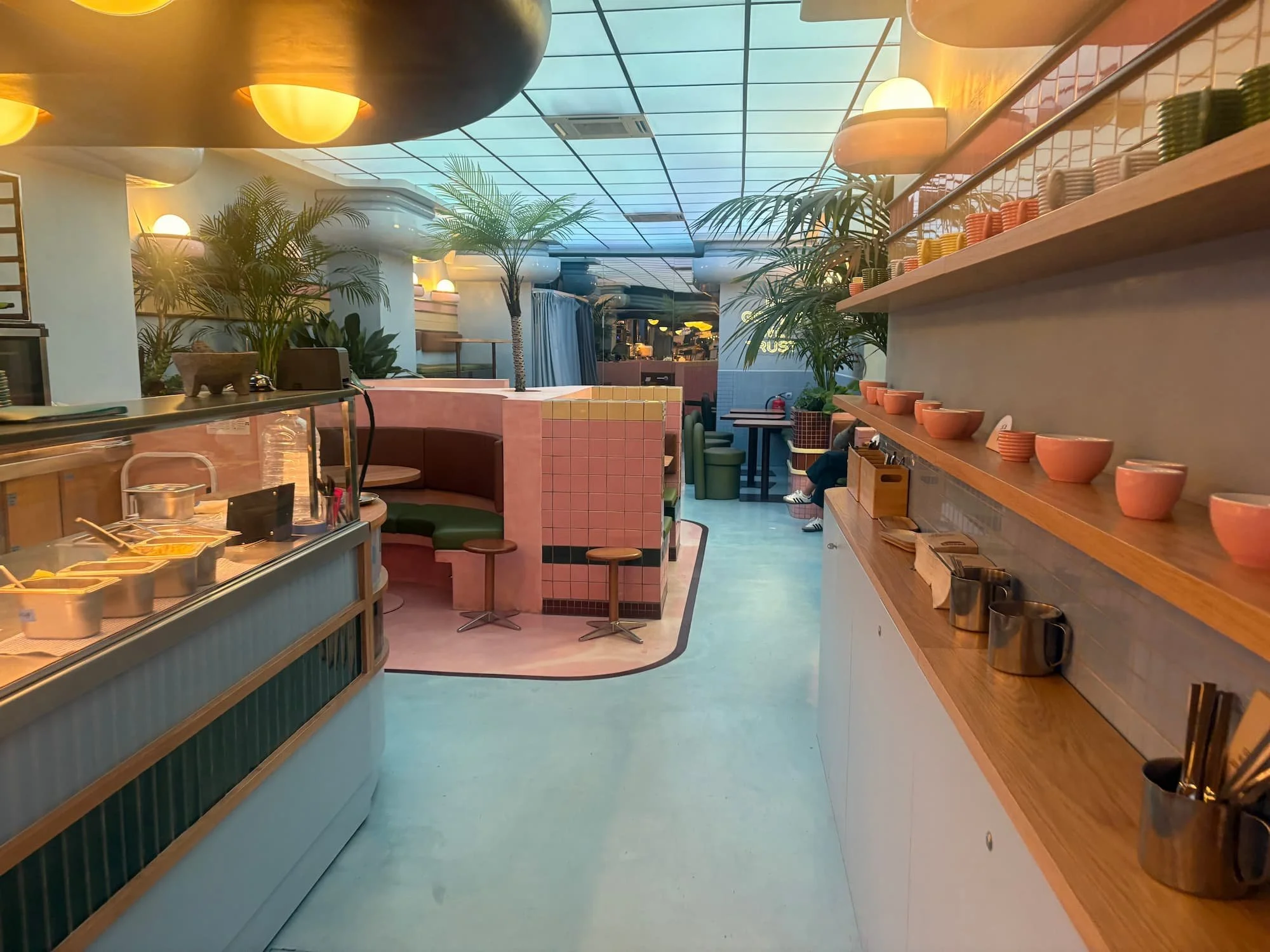 Modern café interior in Barcelona's Eixample district, featuring pastel décor, tropical plants and contemporary seating.