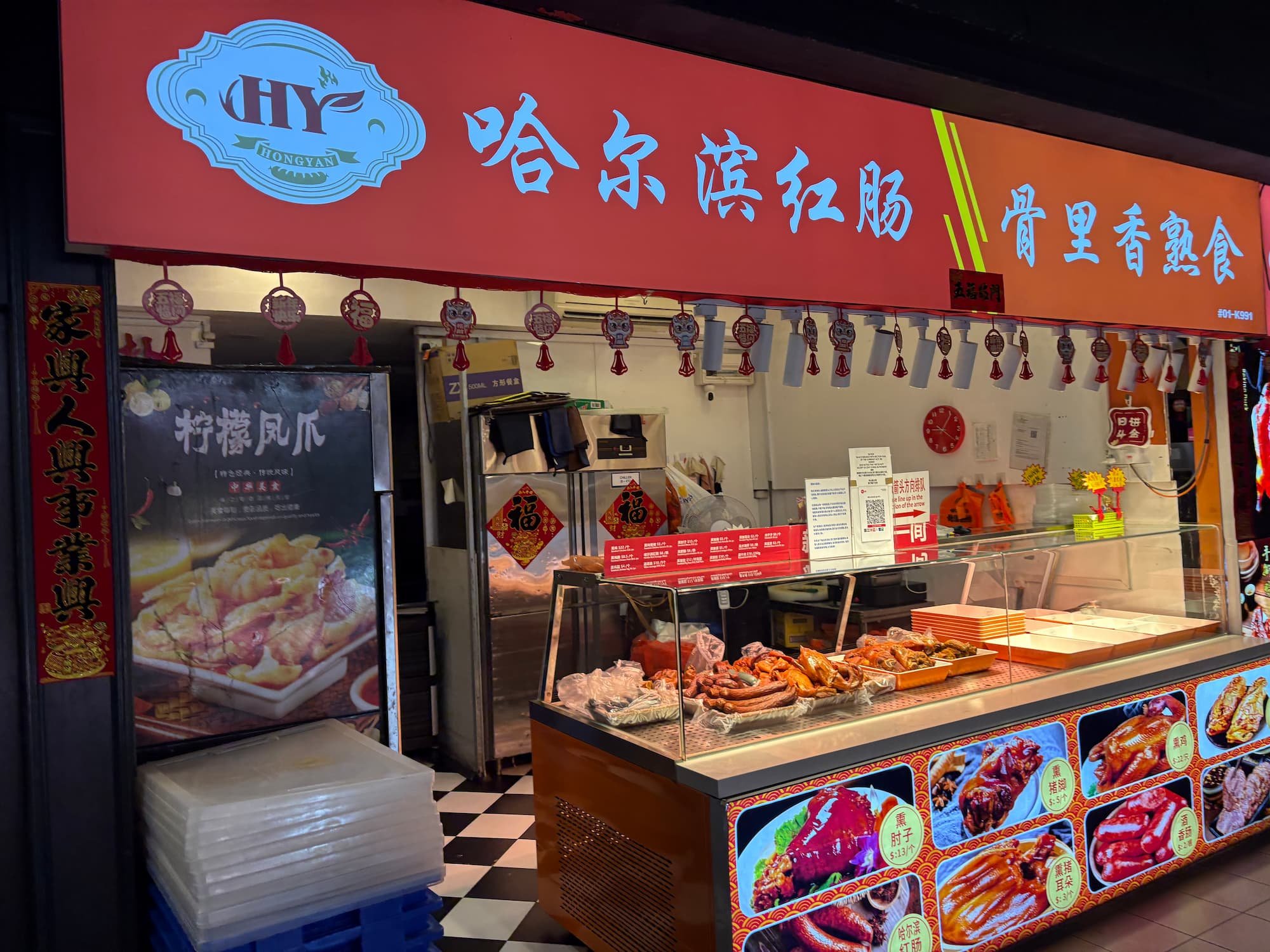 Chinese food stall in Singapore displaying roasted meats and street food dishes inside a busy indoor market.