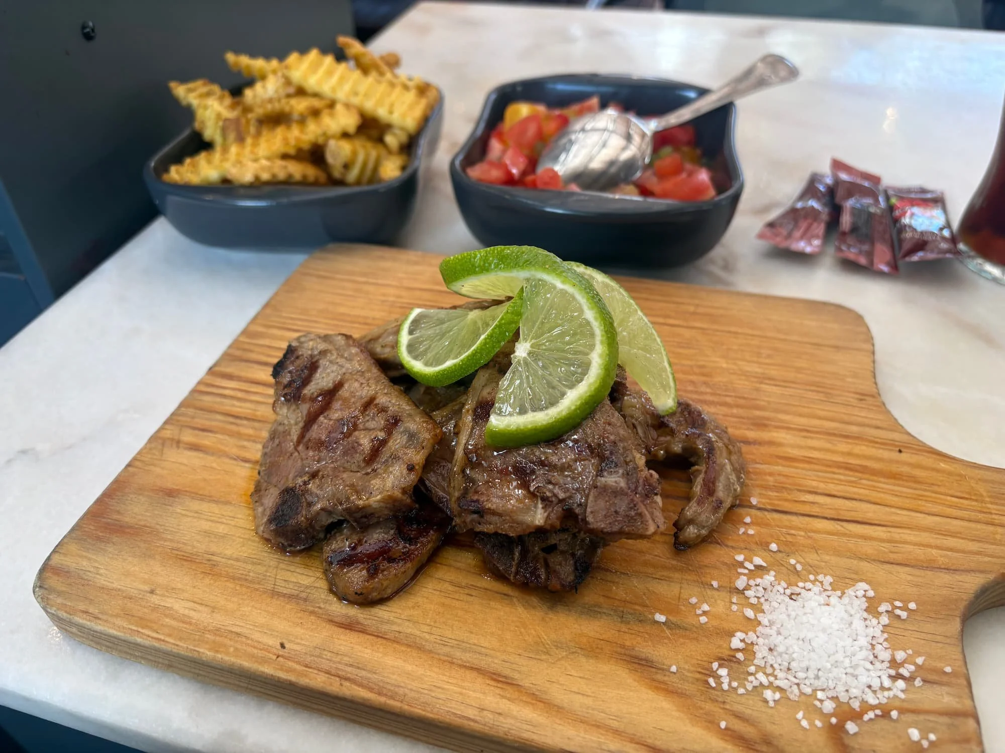 Grilled lamb chops served with seasoned fries, fresh tomato salad and lime at a restaurant in LX Factory, Lisbon.