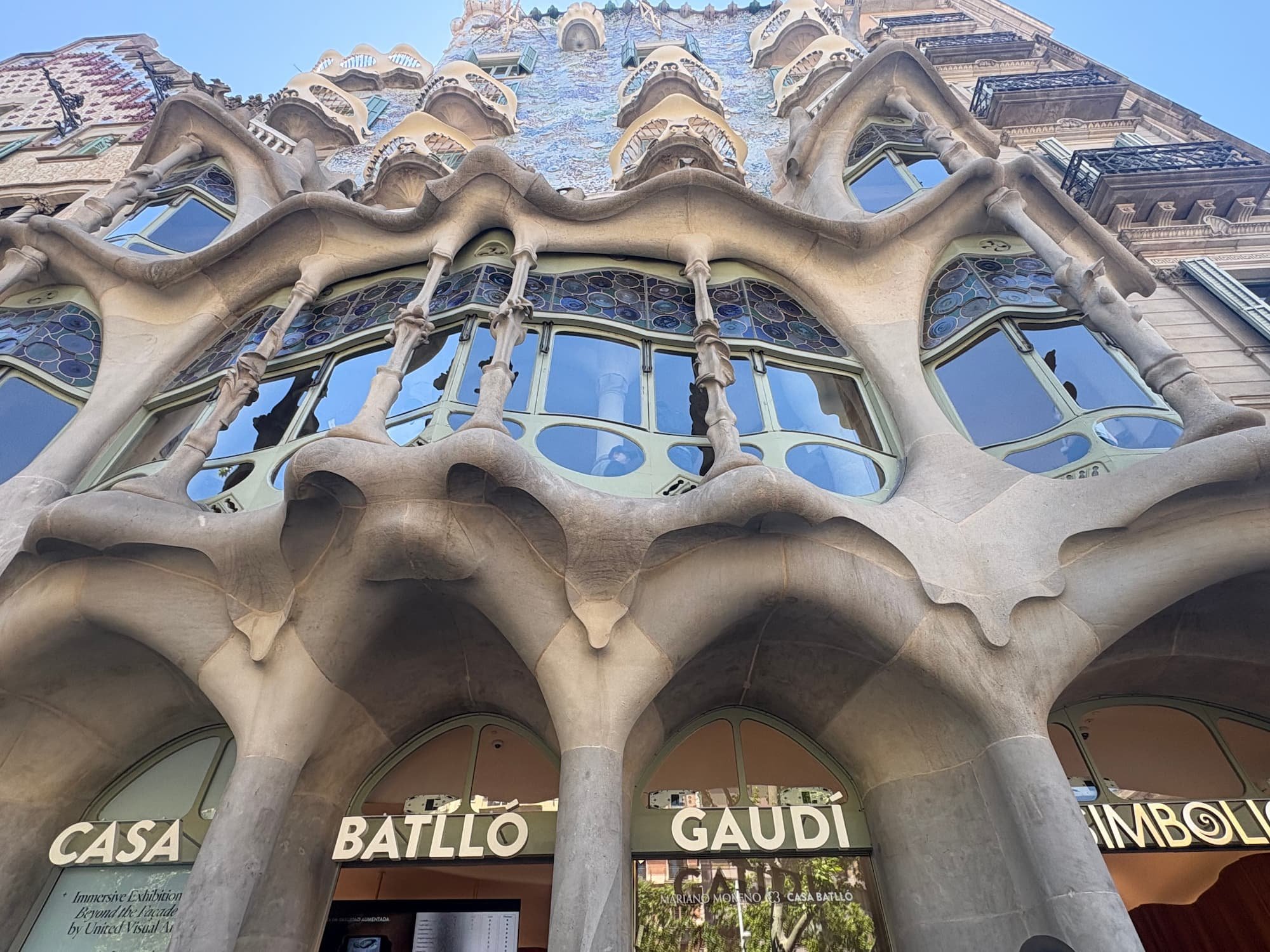 Casa Batlló façade on Passeig de Gràcia in Barcelona, featuring Gaudí's colourful mosaic exterior, curved balconies and dragon-inspired rooftop.
