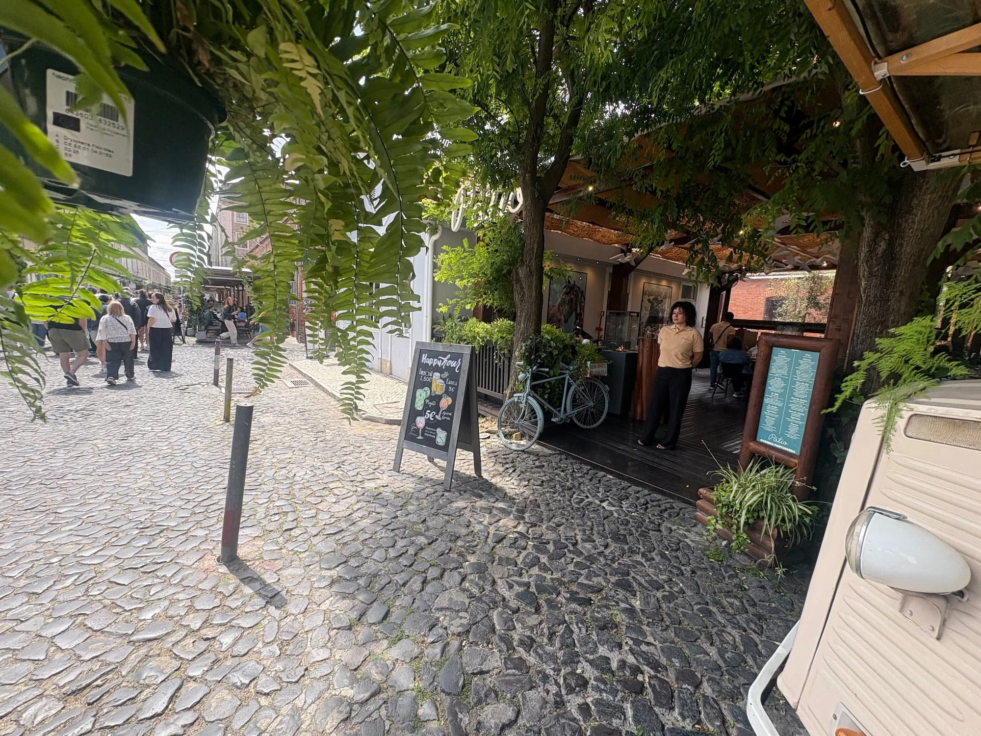 Cobbled street lined with cafés, greenery and independent businesses at LX Factory in Lisbon, Portugal.