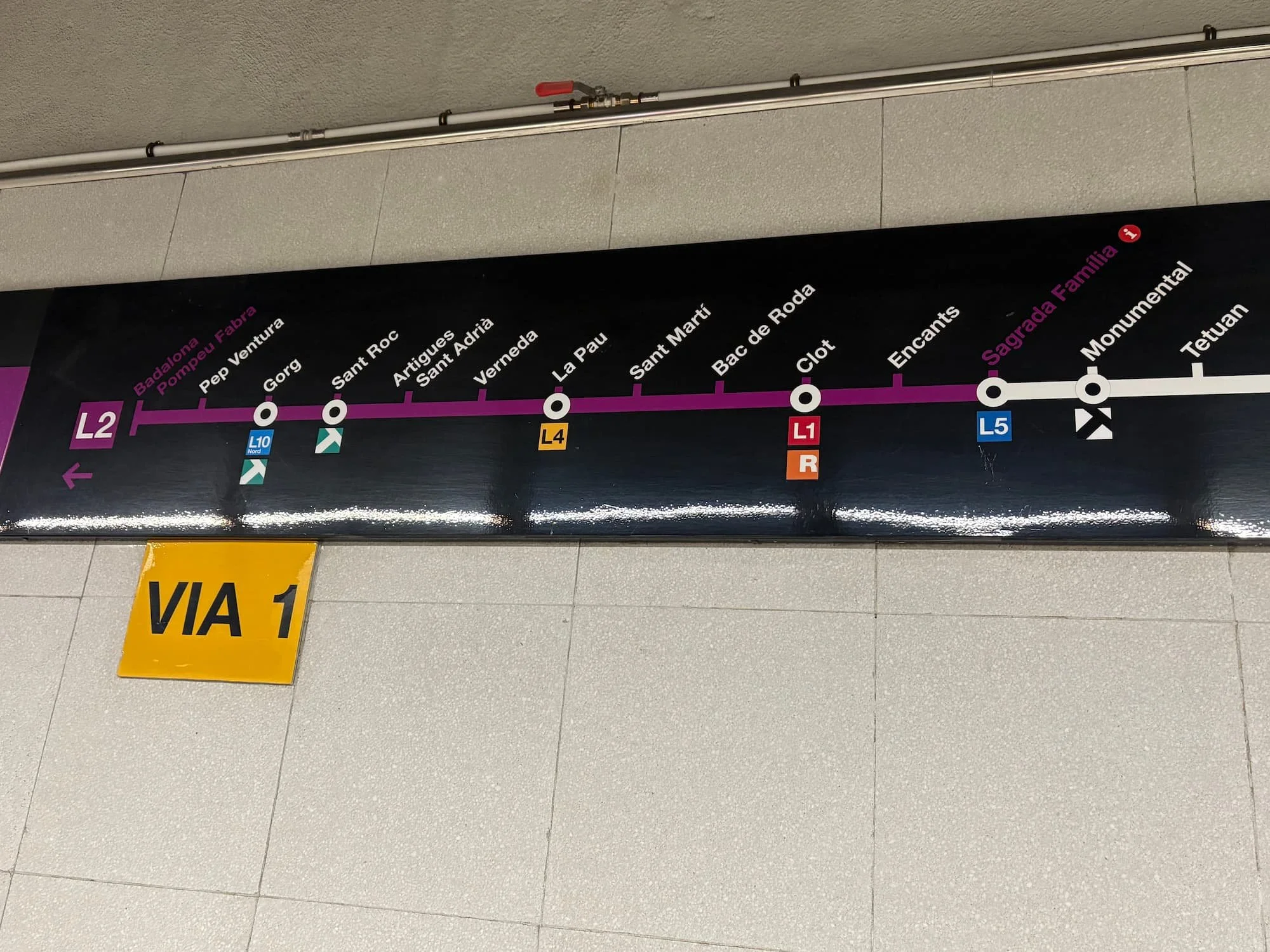 Barcelona Metro route map at a station platform, showing Line 2 and connections to Sagrada Família and other stations.