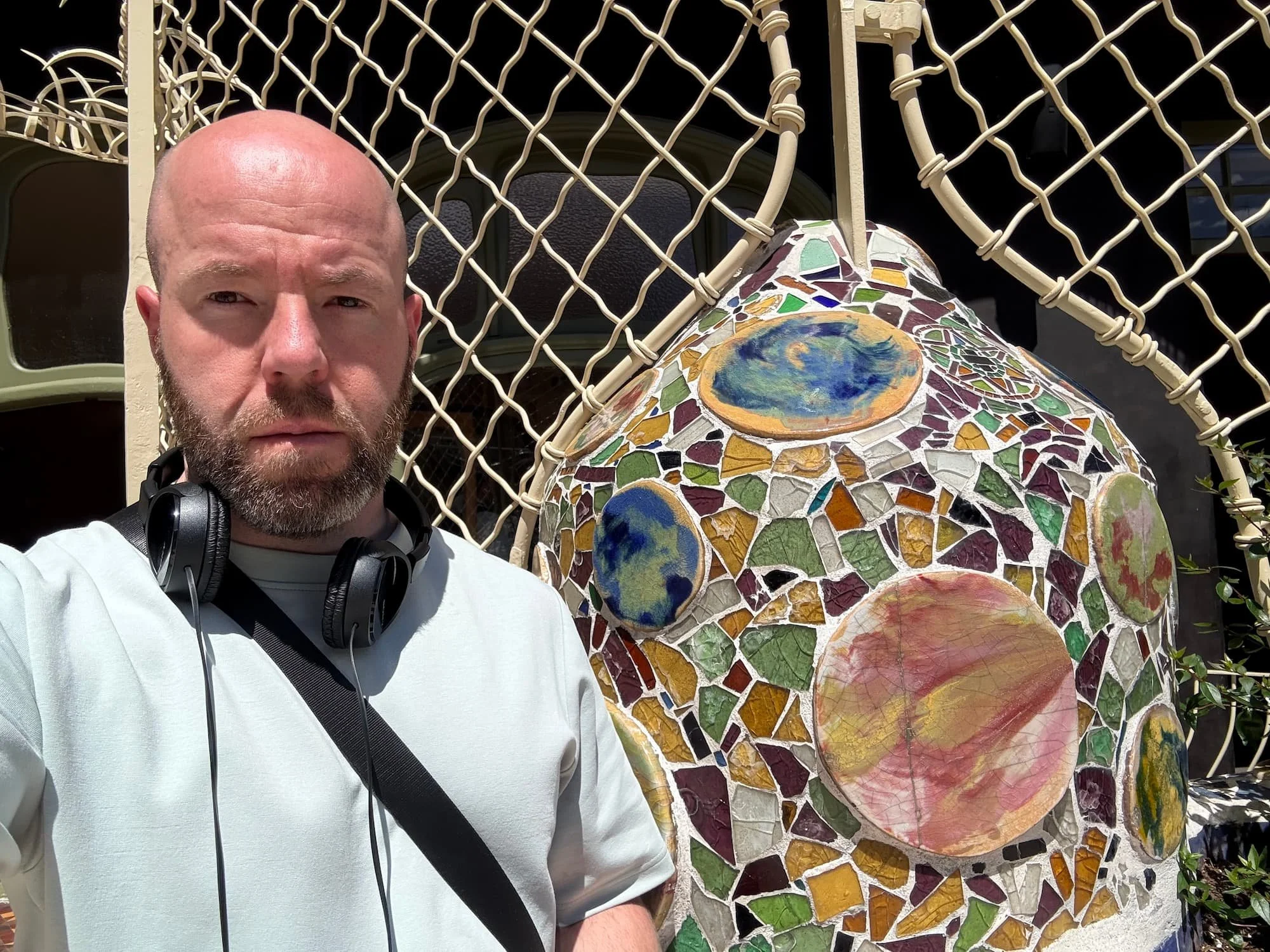 Visitor on Casa Batlló's rooftop beside one of Gaudí's colourful mosaic-covered chimneys and sculptural architectural details.