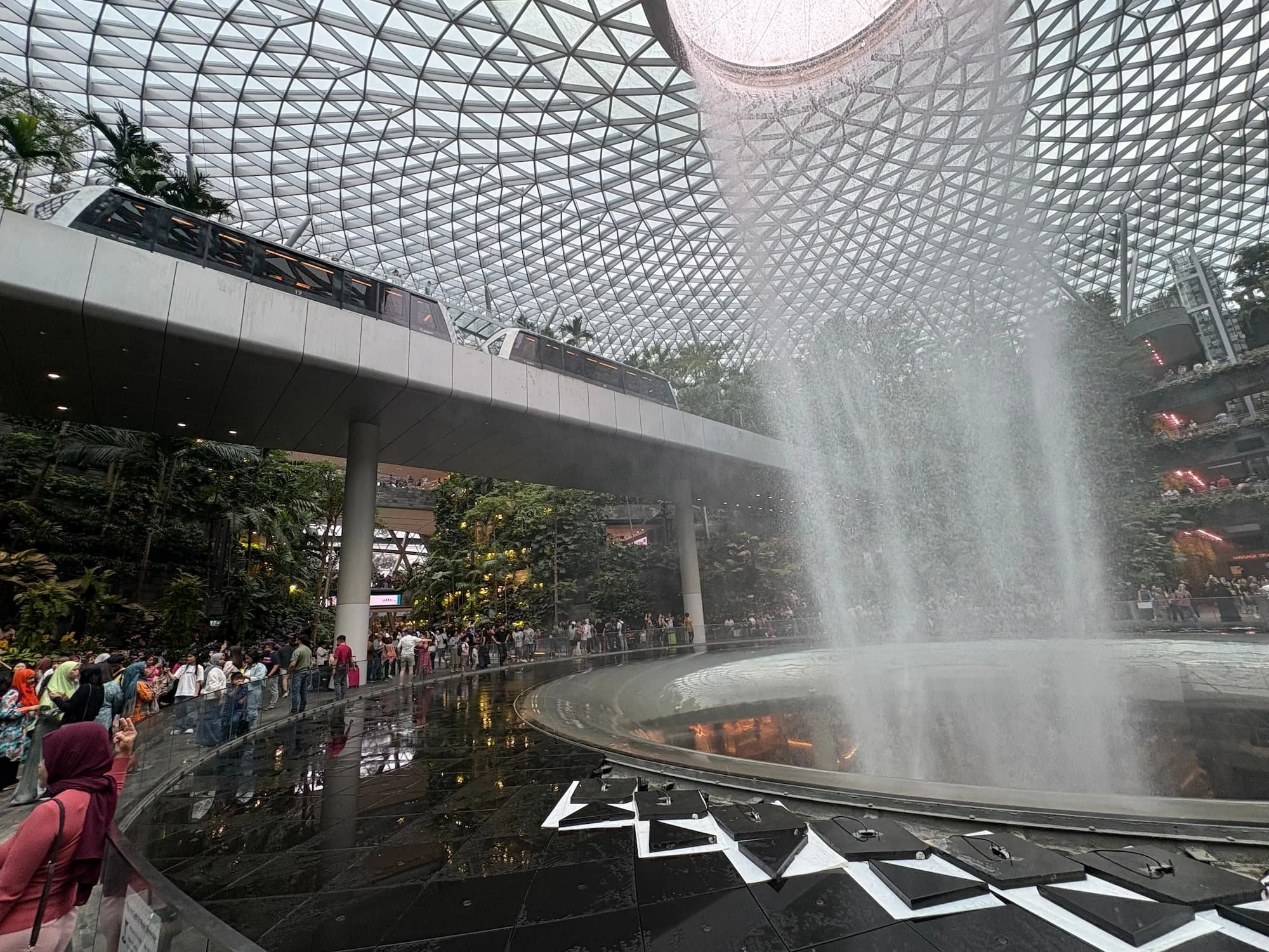 Rain Vortex waterfall at Jewel Changi Airport Singapore with Skytrain passing overhead