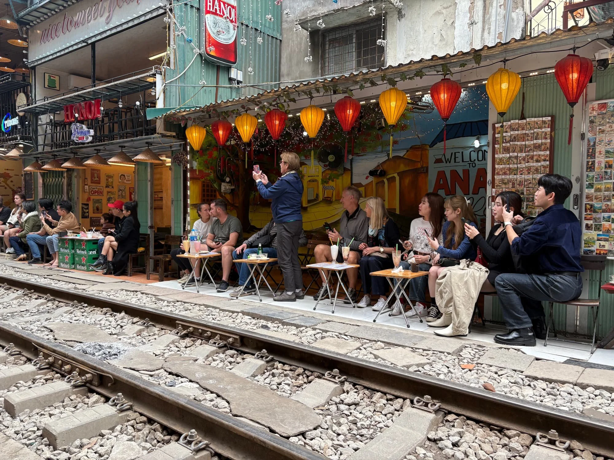 Tourists sat in cafe watching train at Train Street in Hanoi in Vietnam