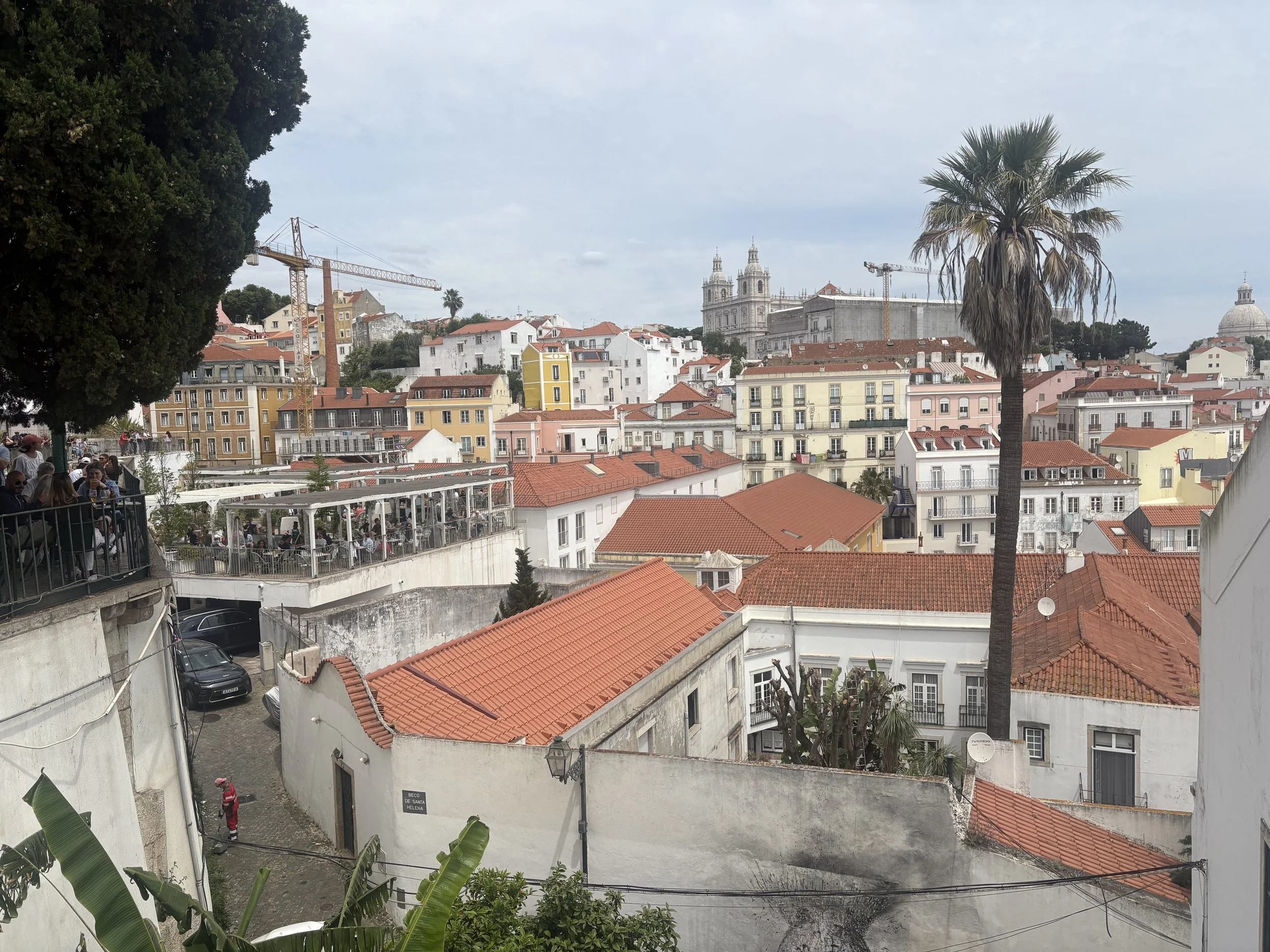 View across Lisbon's colourful rooftops and historic buildings from a hillside viewpoint, showcasing the Portuguese capital's distinctive architecture and skyline.