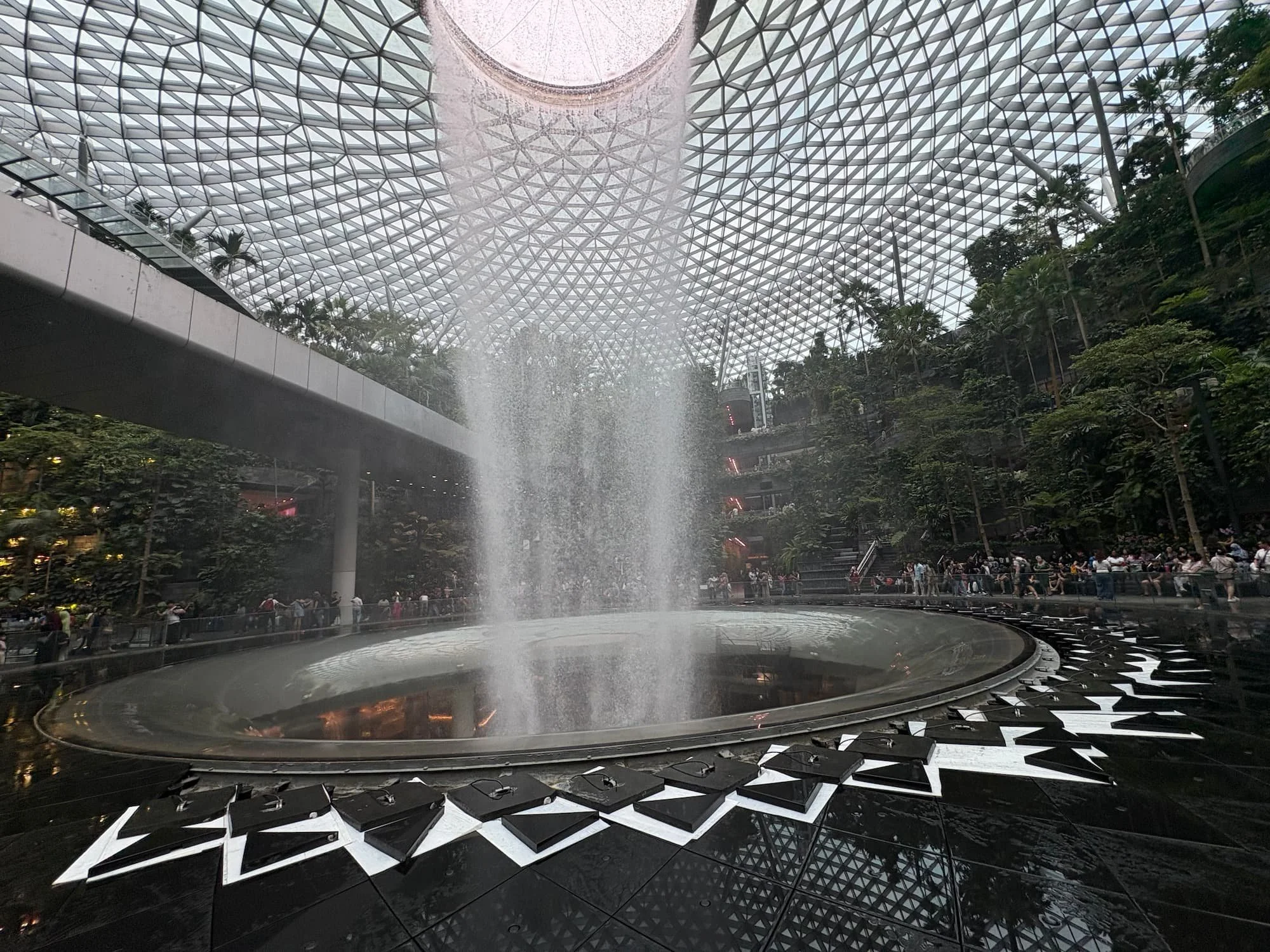 Rain Vortex waterfall inside Jewel Changi Airport Singapore surrounded by indoor rainforest and glass dome ceiling