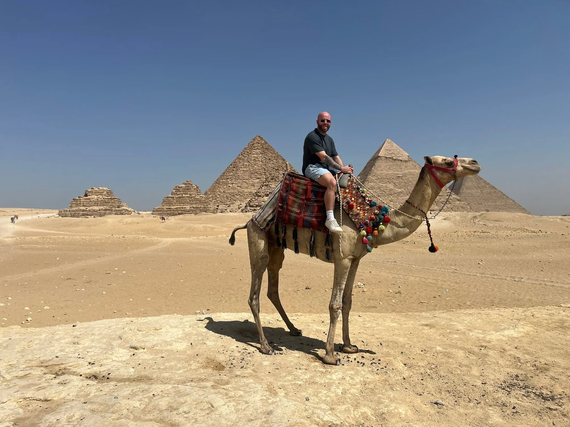 Tom Henty riding a camel at viewpoint at Giza Plateau in Egypt