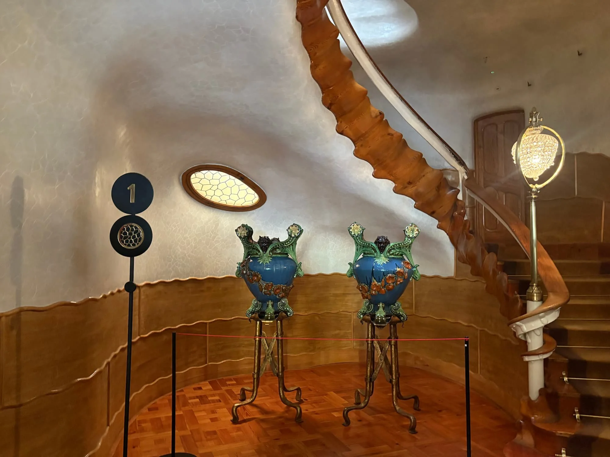 Curved wooden staircase and organic interior design inside Casa Batlló's Noble Floor, featuring Gaudí's flowing architecture and decorative ceramic vases.