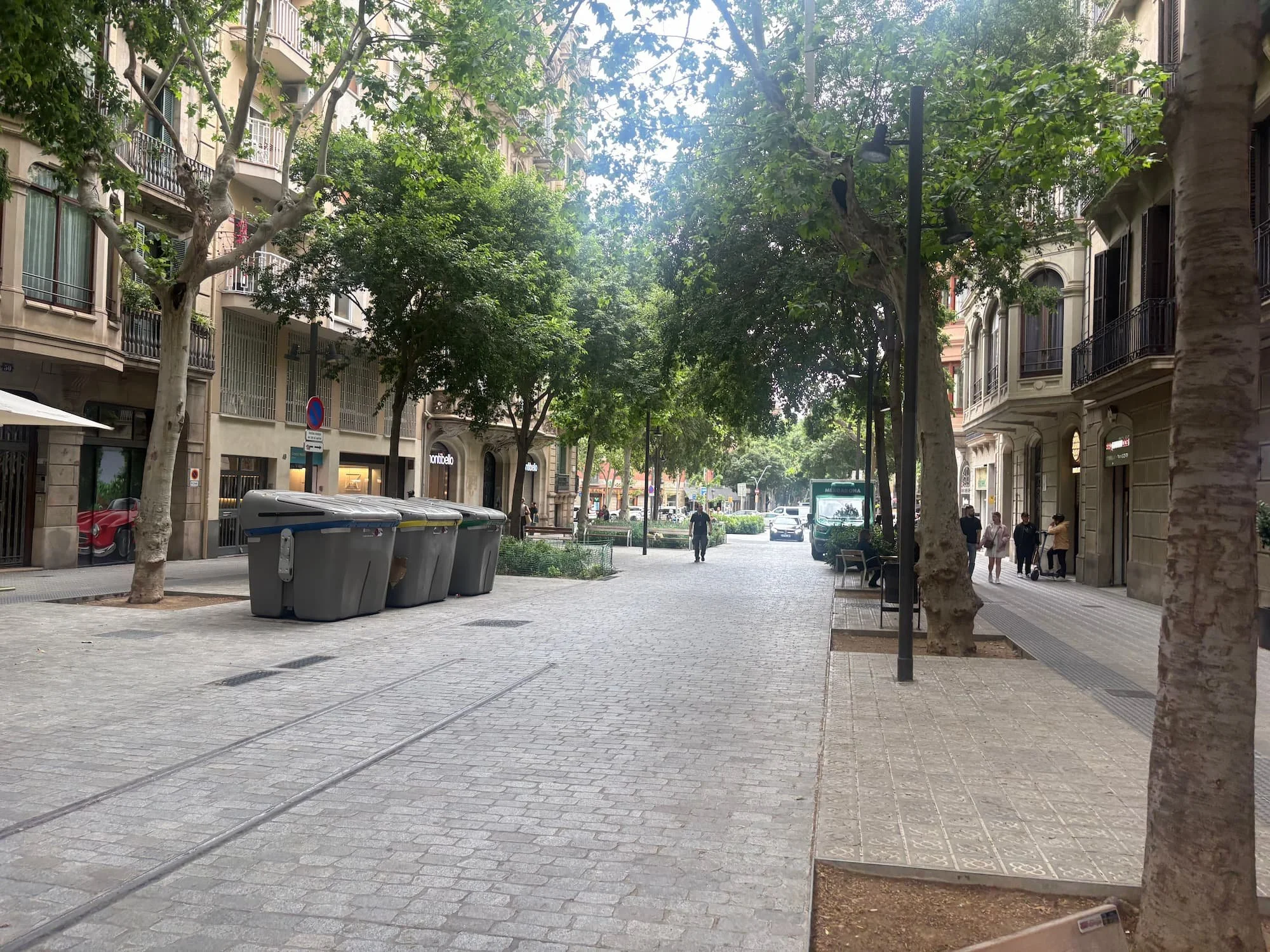 Tree-lined street in Barcelona's Eixample district, featuring elegant apartment buildings and wide pedestrian-friendly boulevards.