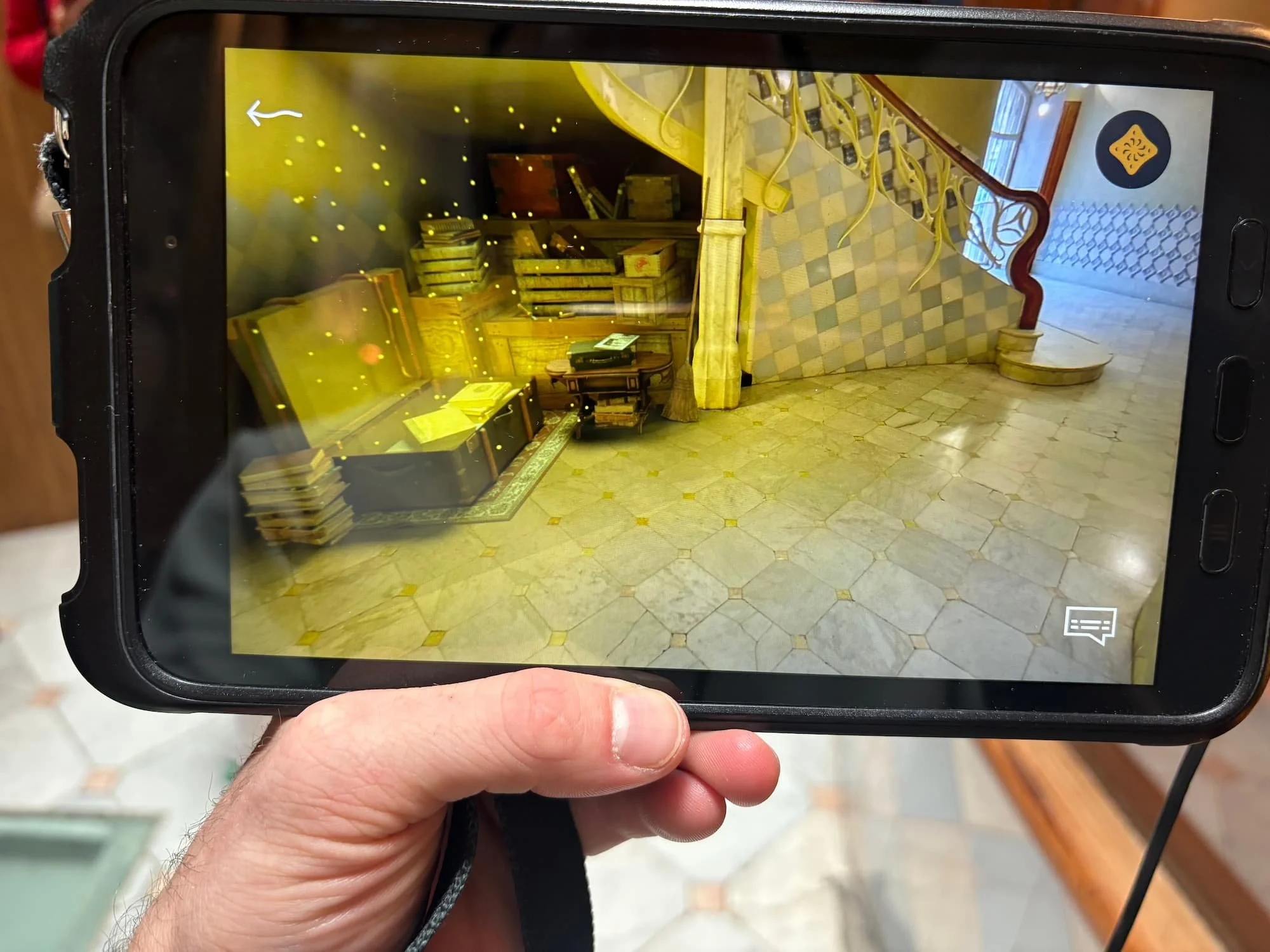 Immersive tablet experience at Casa Batlló showing augmented reality visuals layered over Gaudí's interior staircase and architecture.