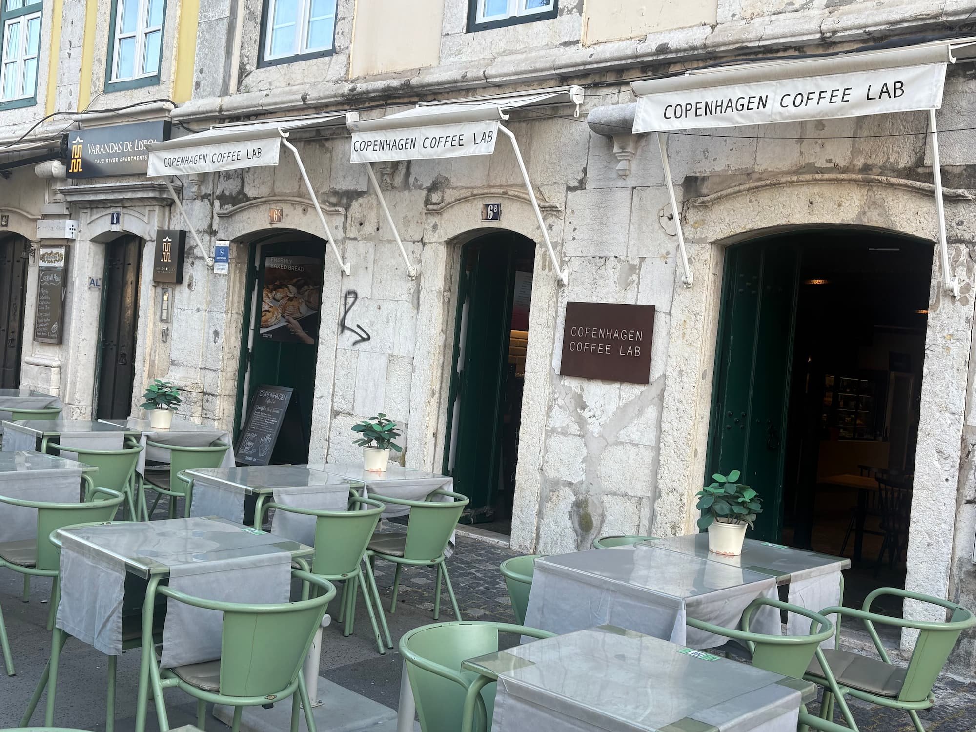 Exterior of Copenhagen Coffee Lab in Lisbon, Portugal, with outdoor seating in one of the city's historic streets