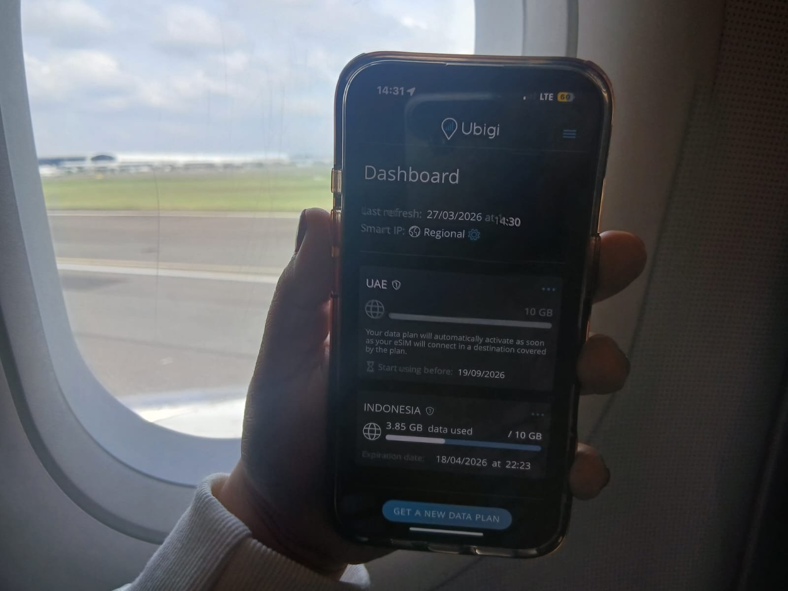 Ubigi eSIM connecting instantly on arrival in Indonesia with phone in airplane showing data active