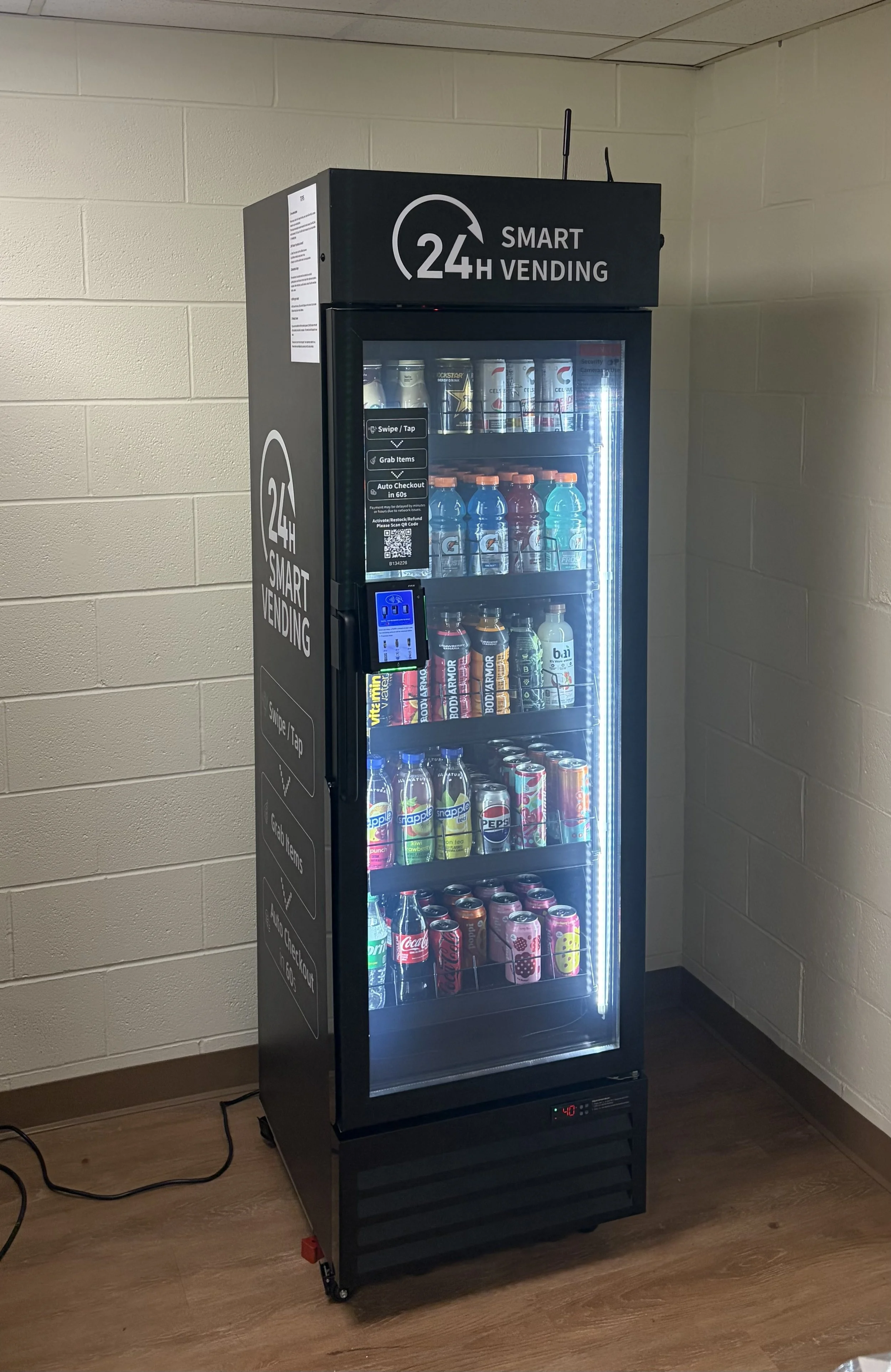 HAHA Mini Smart Cooler fully stocked with beverages including Gatorade, Celsius, and soda cans, labeled “24H Smart Vending” and featuring a touchscreen and glass door.
