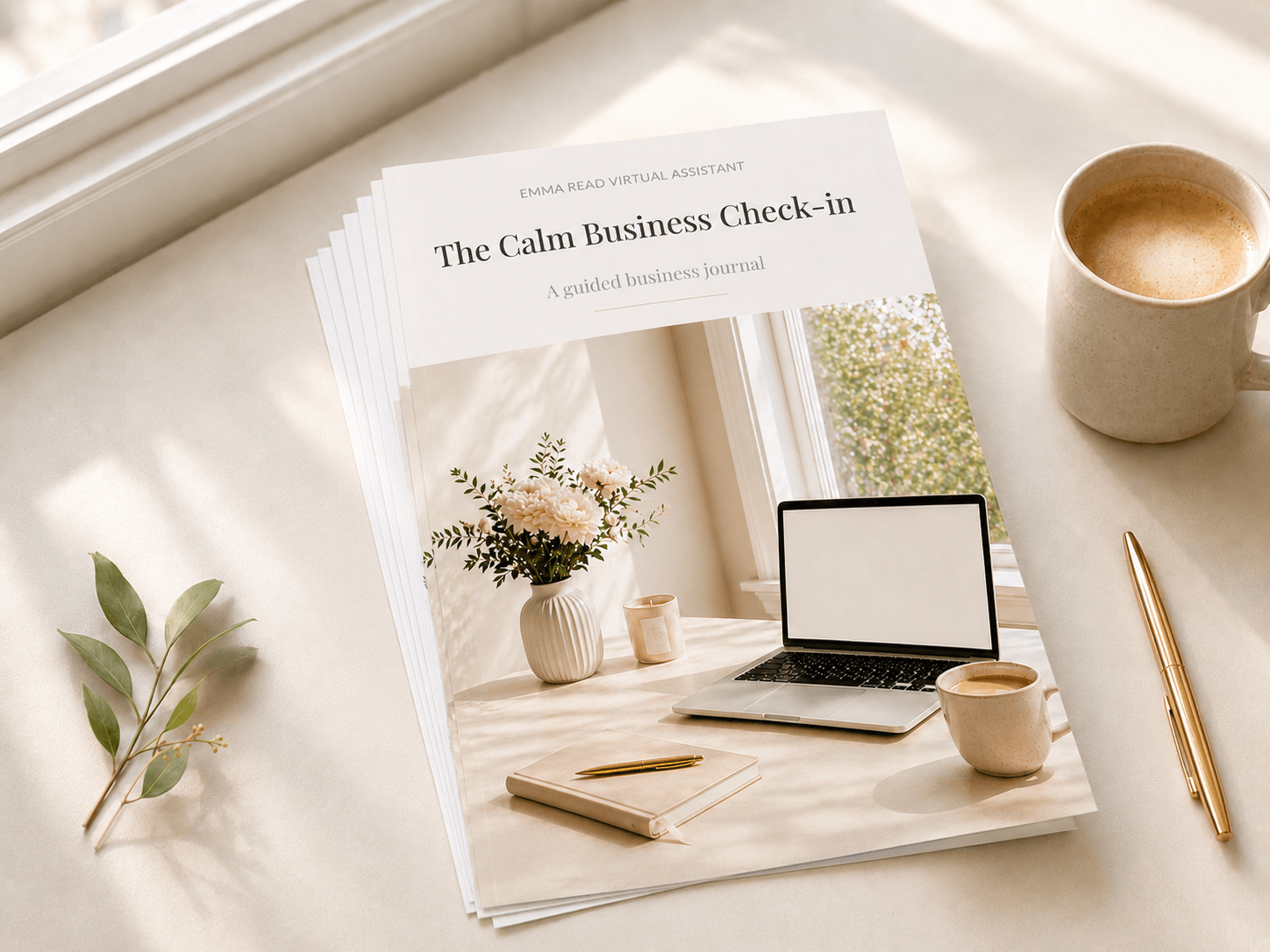 The Calm Business Check-in printed as a slim stack of loose pages, styled with a caramel latte, gold pen and green leaves.