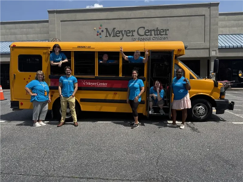 Meyer Center bus and drivers in front of school.
