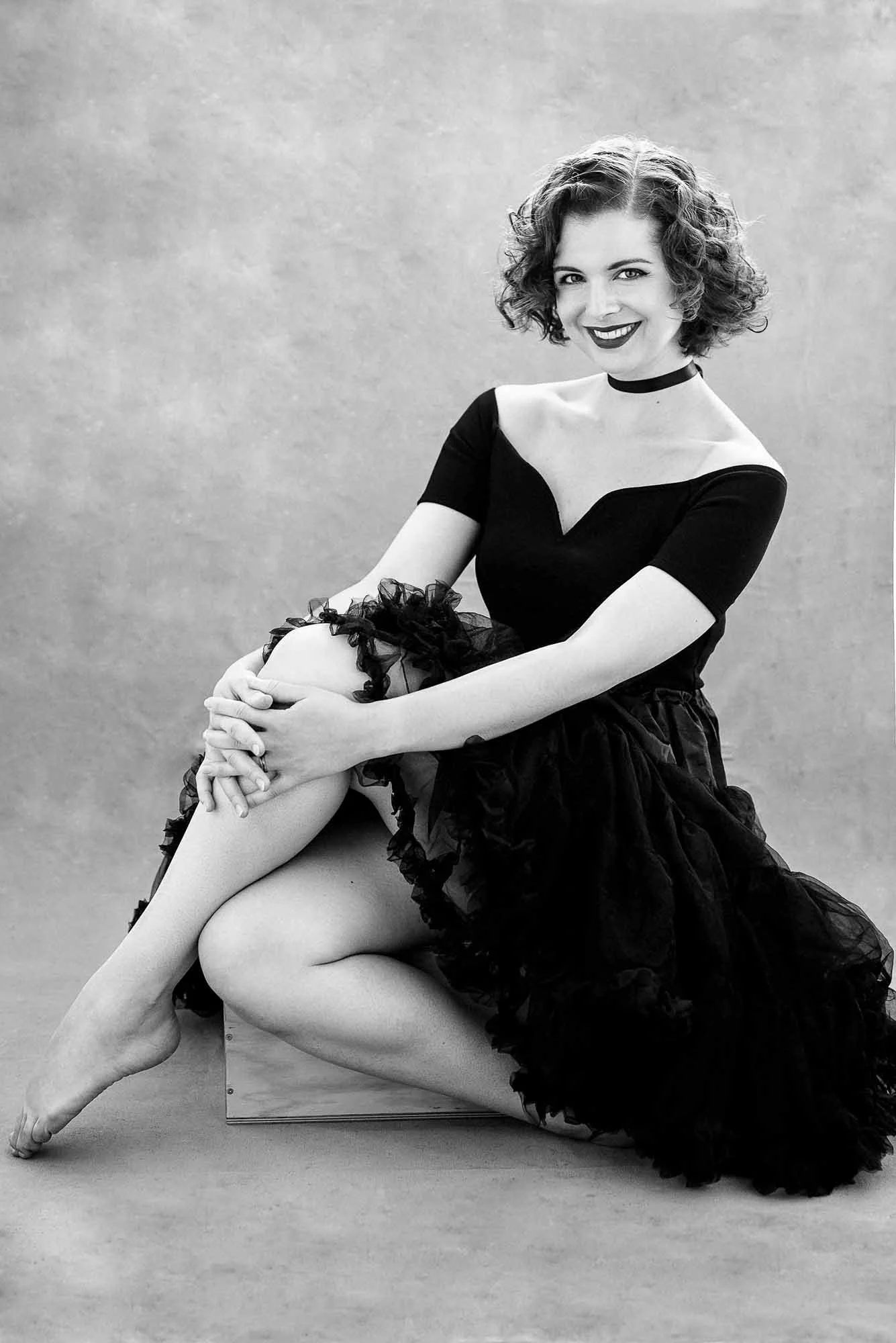Curly-haired woman posing with another woman in black tutu. Creative and joyful duo portrait with fashion energy.