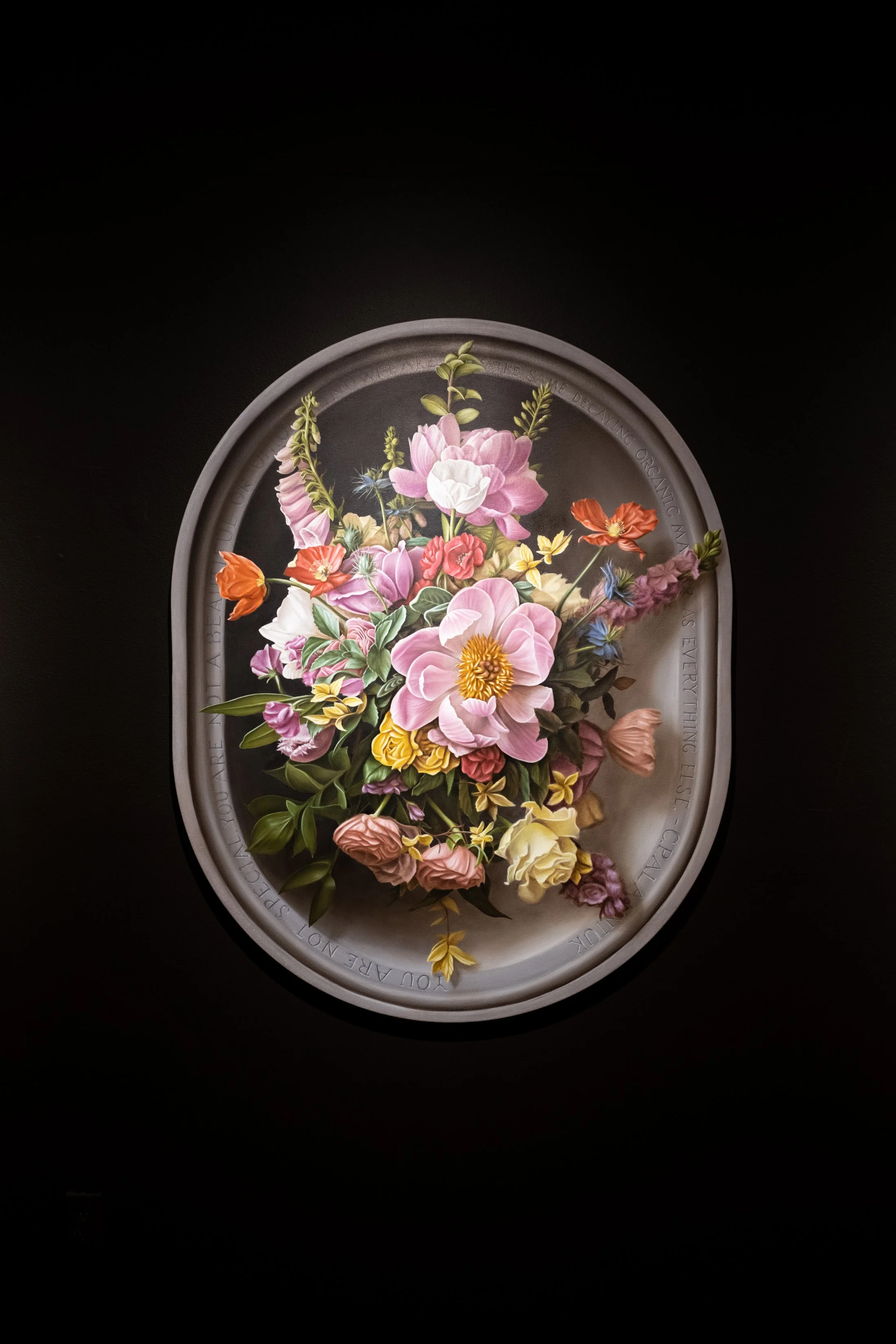 A framed floral artwork featuring a bouquet of pink, white, yellow, purple, and orange flowers on a dark background.