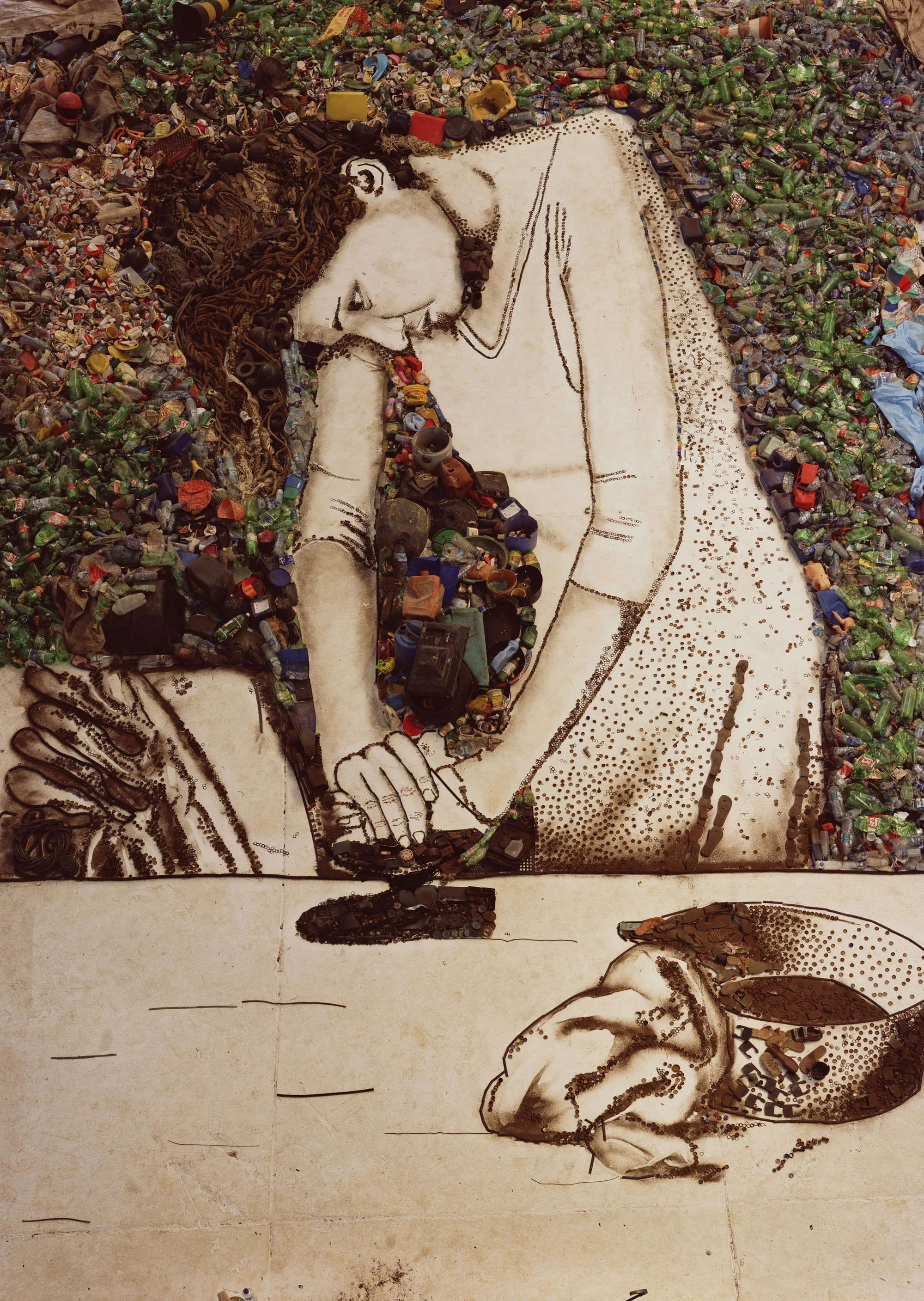 An artwork depicting a woman resting her head on her hand, created using arranged garbage and trash items on a tiled surface, with an outlined sketch to define features.