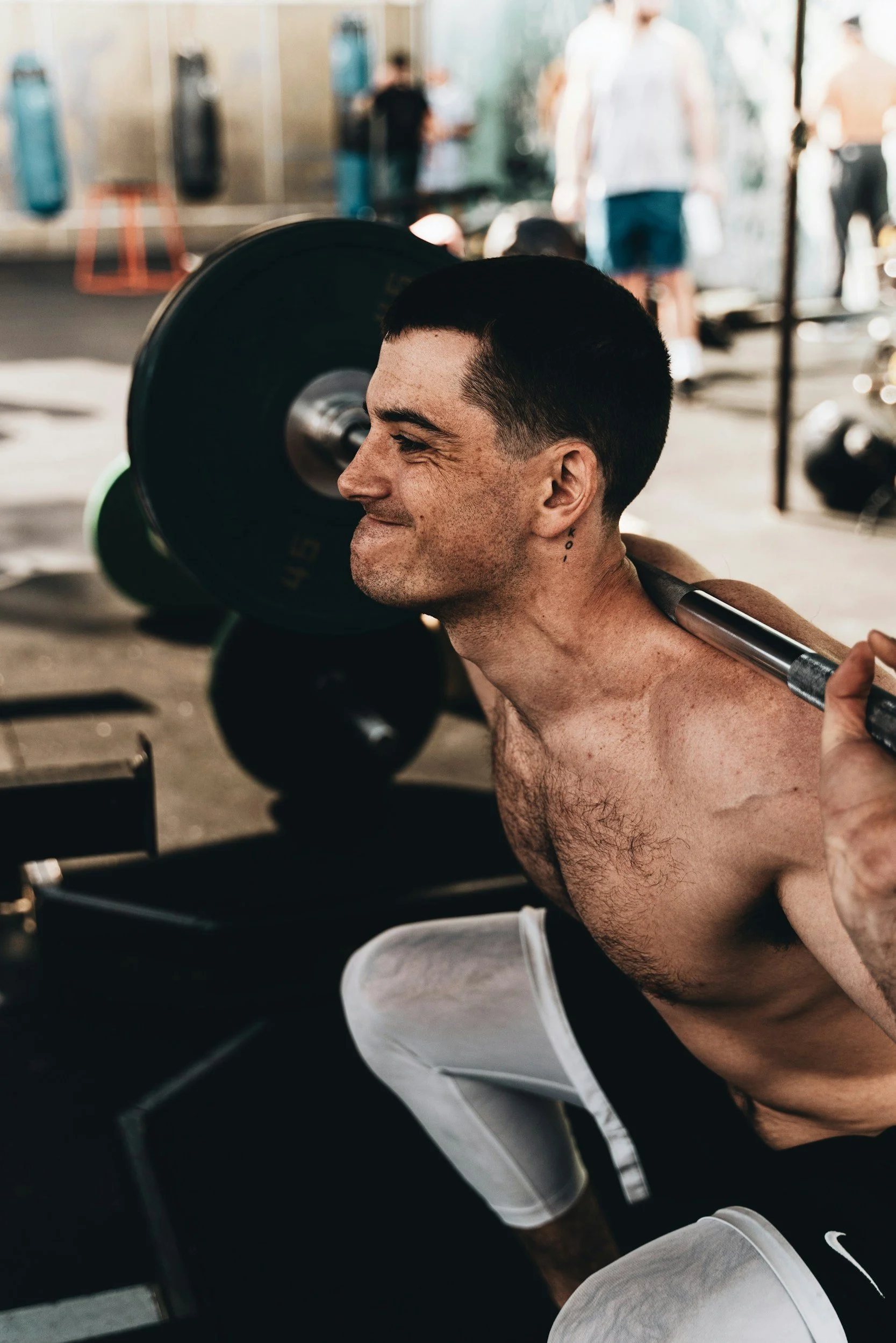 Shirtless man squatting with a barbell