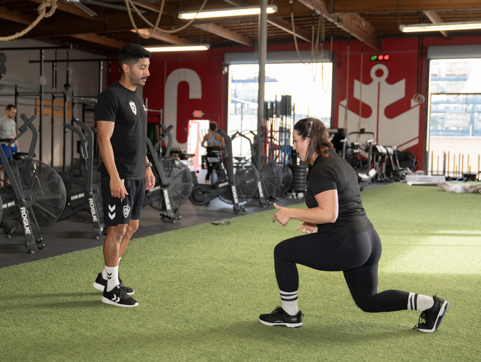 Female physical therapist demonstrating a lunge for athletic male client