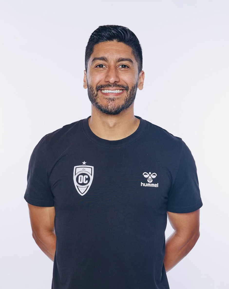 Male physical therapist with short black hair, short black facial hair, and wearing a black jersey shirt