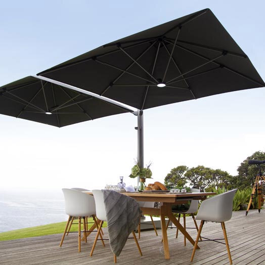 Double umbrella providing shade over an outdoor table set with food