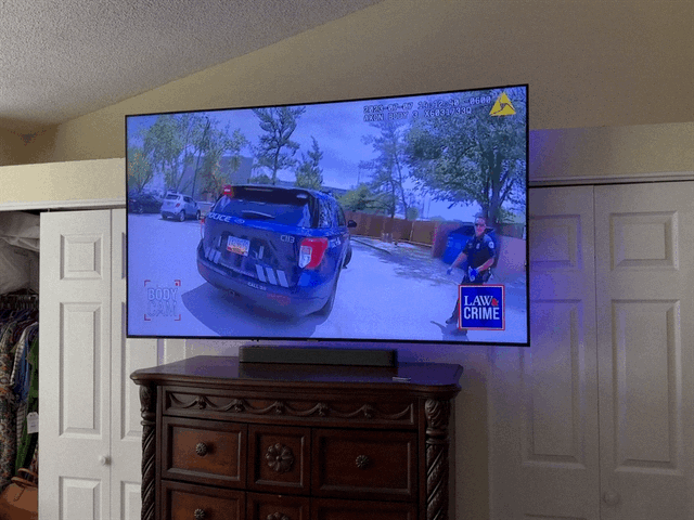 Television displaying a police vehicle and an officer in a residential outdoor setting.