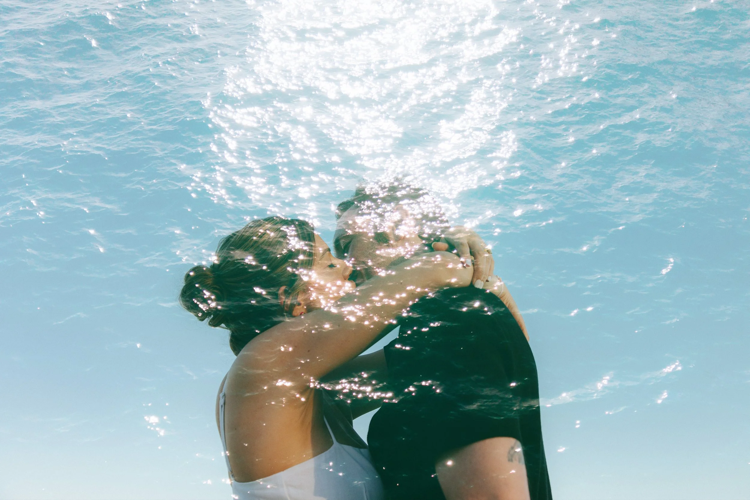 Ethereal image couple kissing and sun reflecting on the ocean