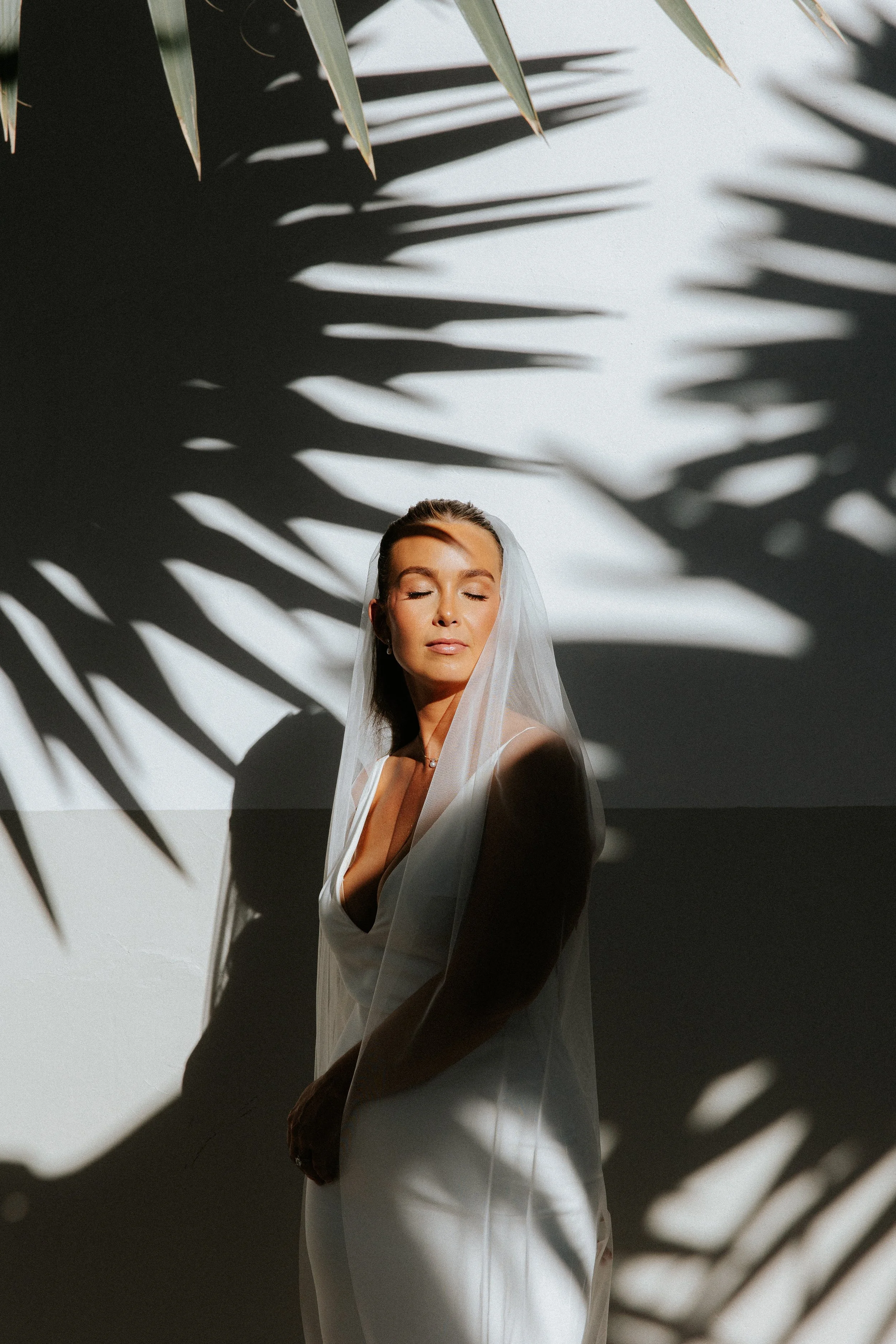 Bride posing in harsh sun with palm shadows