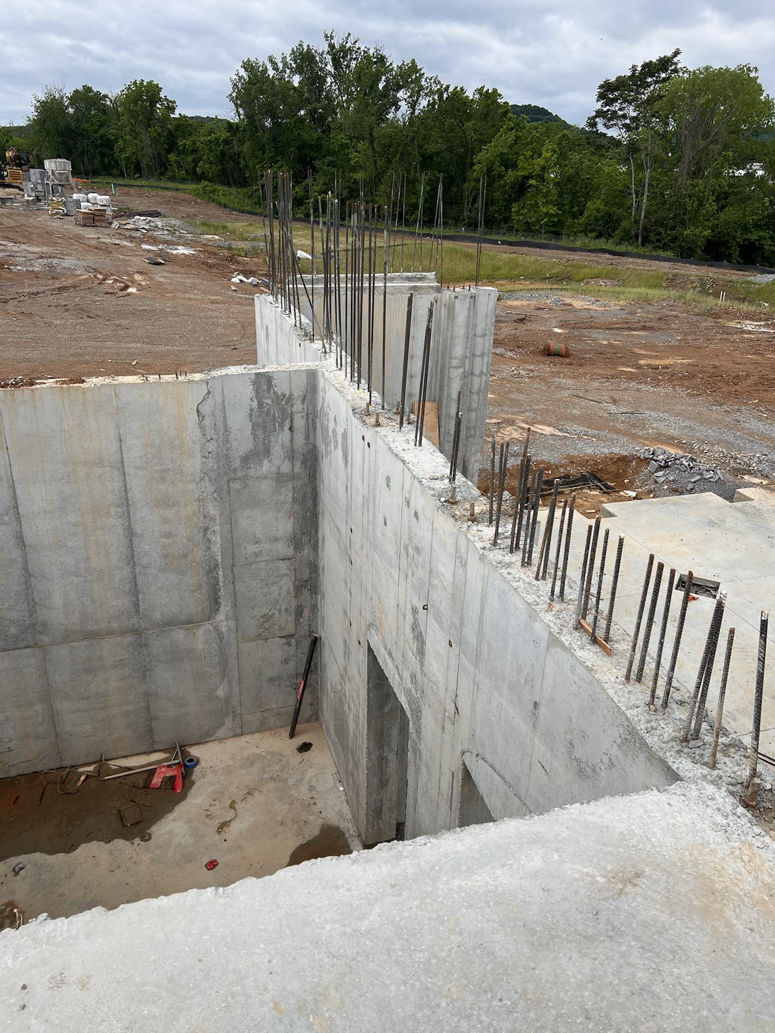Cast-in-place concrete foundation walls of a commercial below-grade level before backfill, showing the type of bare concrete wall that requires below-grade waterproofing prior to being buried.