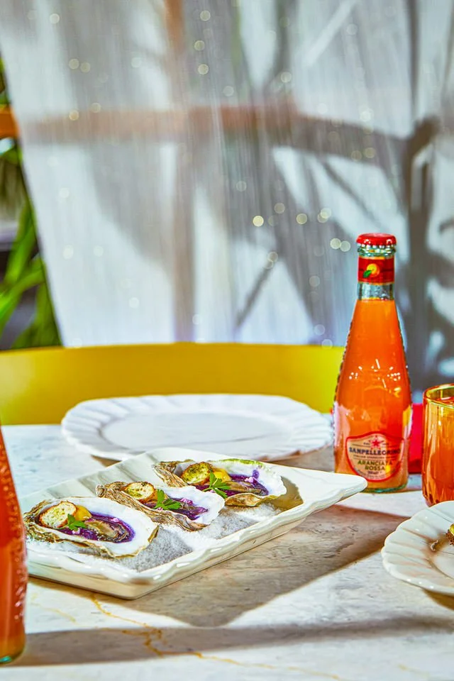 Bir tabak istiridye ve bir şişe gazlı içecek içeren masa düzeni.

