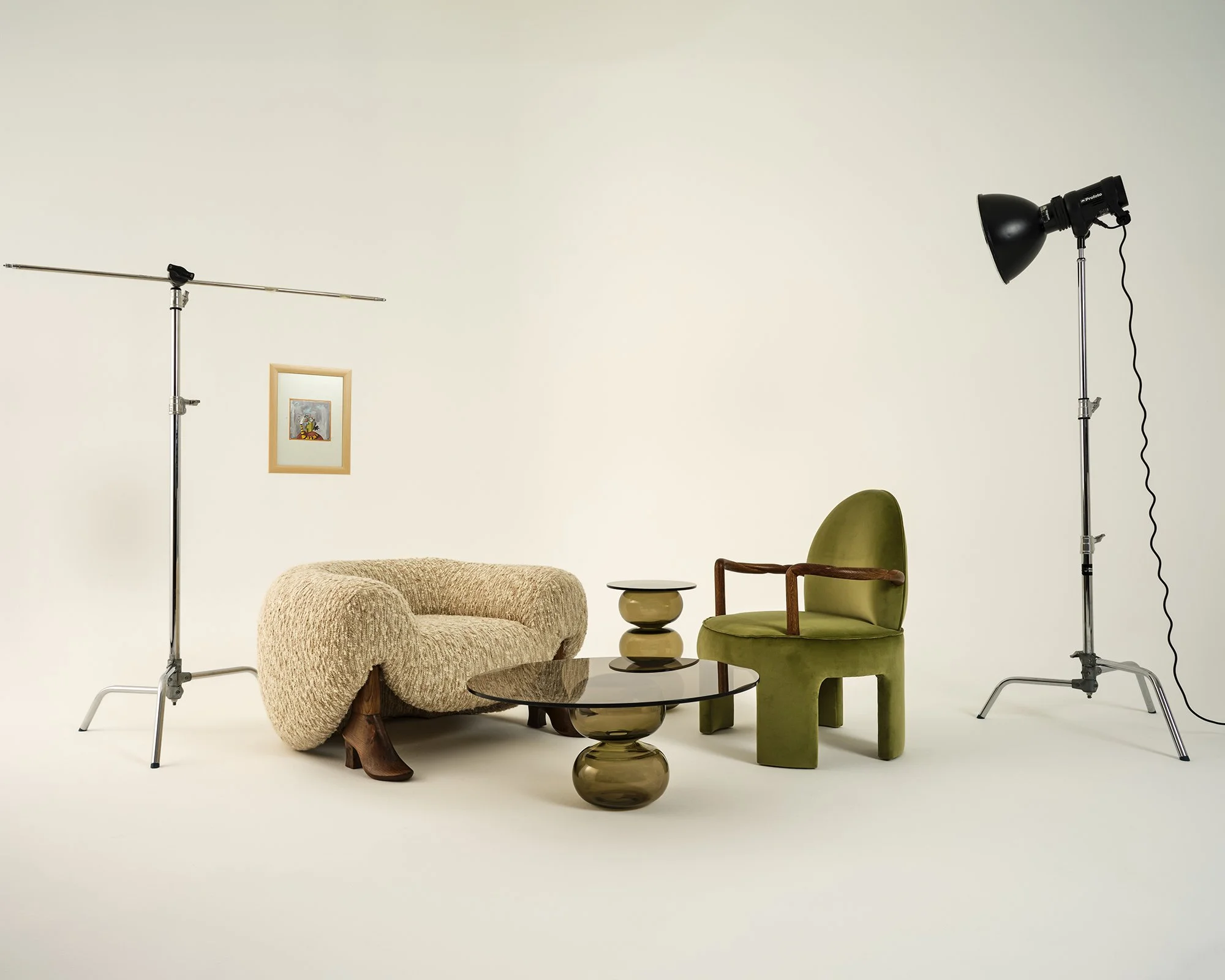 Her iki yanında birer tane siyah stüdyo ışığı bulunan bir stüdyo kurulumu; ışıklar bej peluş bir koltuk ile yeşil kadife bir berjere yöneltilmiş. Aralarında dekoratif bir vazo bulunan yuvarlak cam bir sehpa ve yuvarlak üst yüzeye sahip küçük siyah bi
