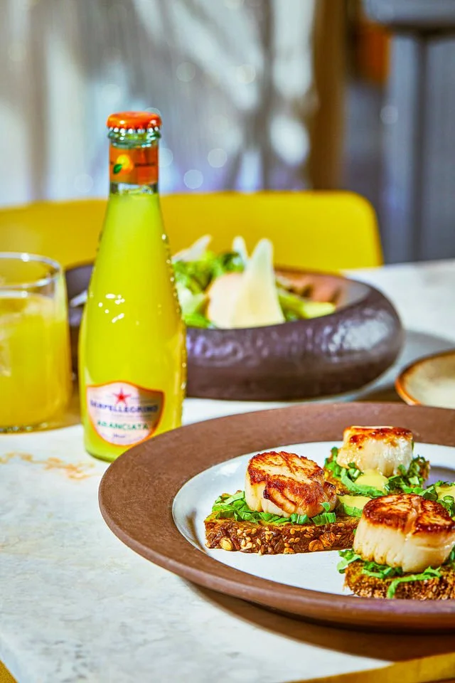 Izgara sebzeler, midye ve suşi ruloları içeren sarı masa örtüsüne sahip bir masa düzeni.