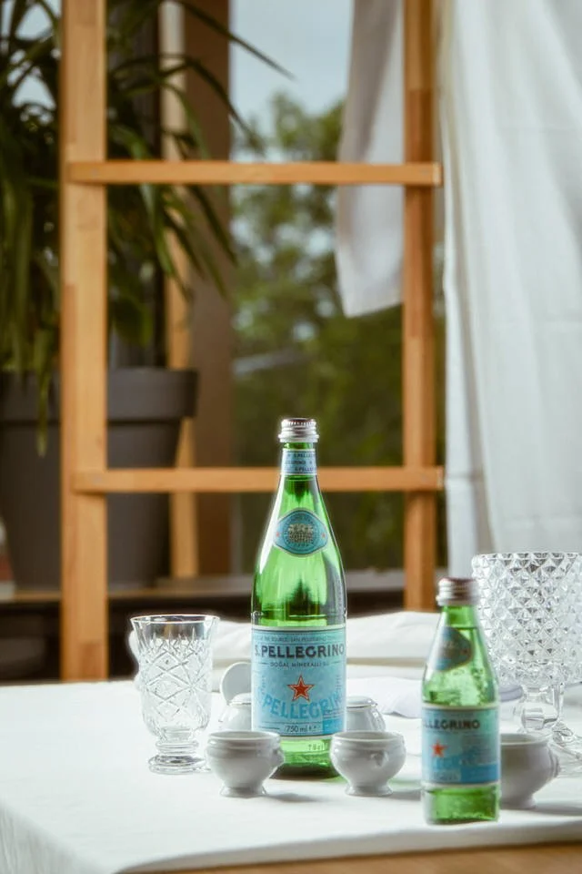 Bir tabak istakoz risottosu, yanında su bardağı, mum ve içecek şişesi bulunan masa düzeni.

