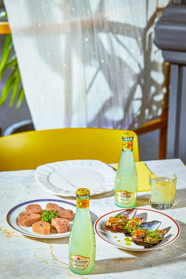 Meze tabakları, iki şişe limonata ve bir bardak limon içeceği içeren masa düzeni.

