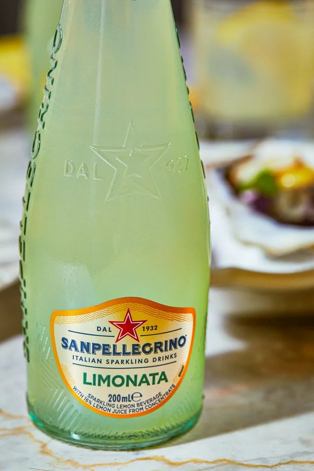Yemek masasının üzerinde bir şişe limonata.

