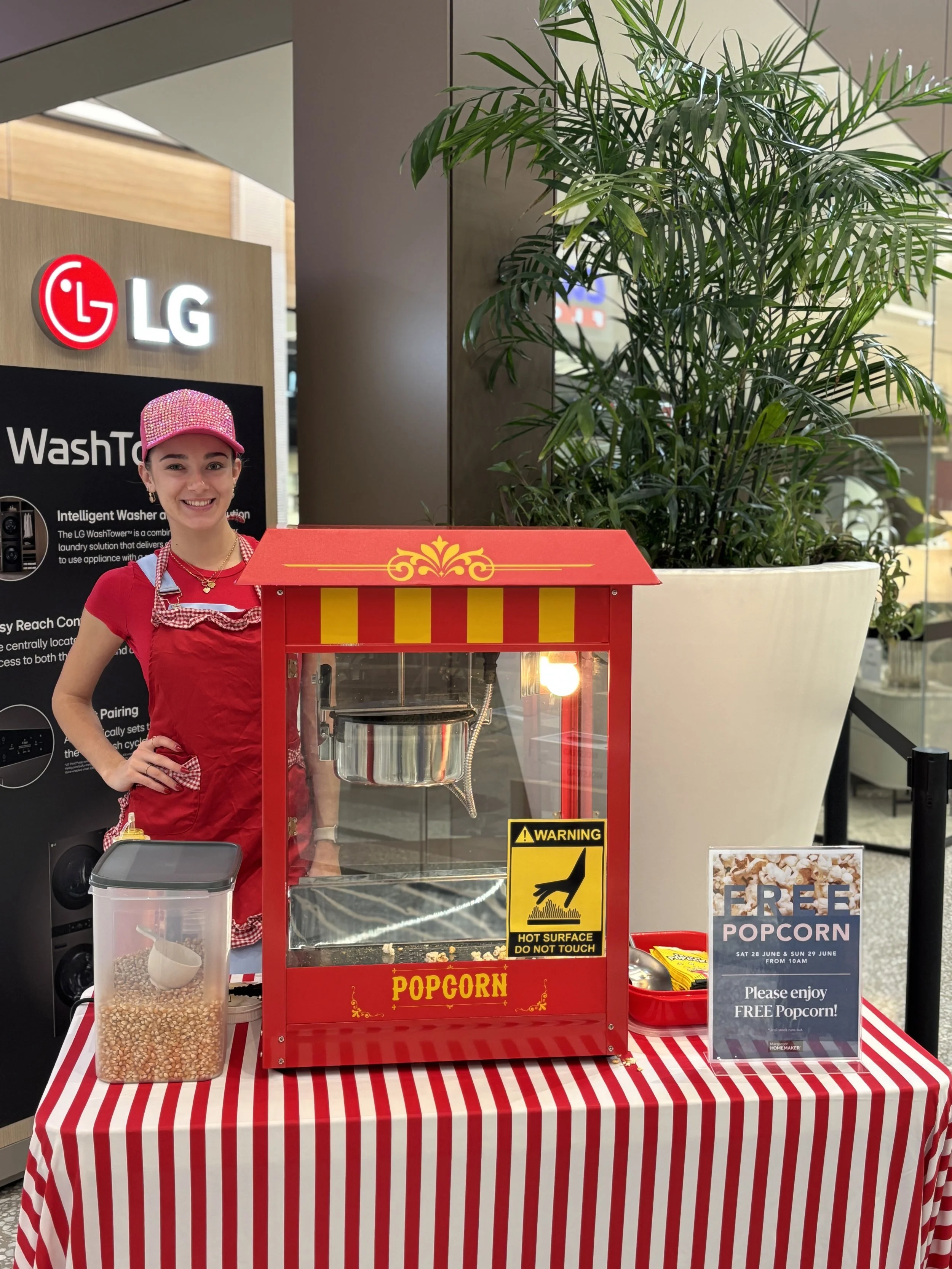 Popcorn machine setup with operator in red costume at shopping centre event