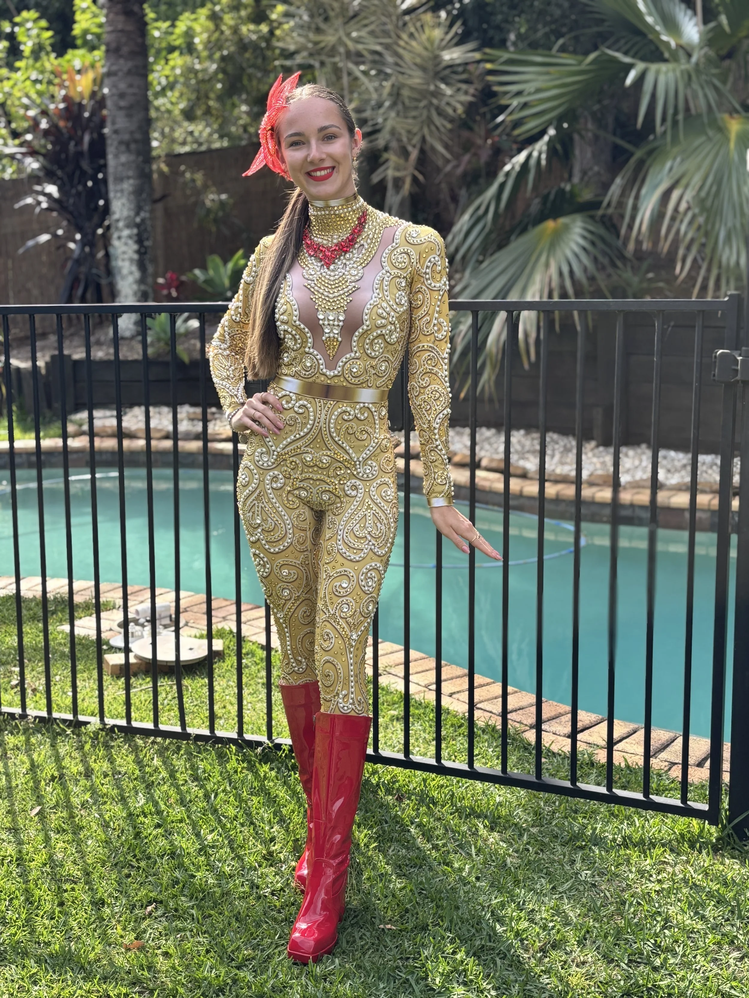 A performer dressed in a gold embellished outfit with red accessories.