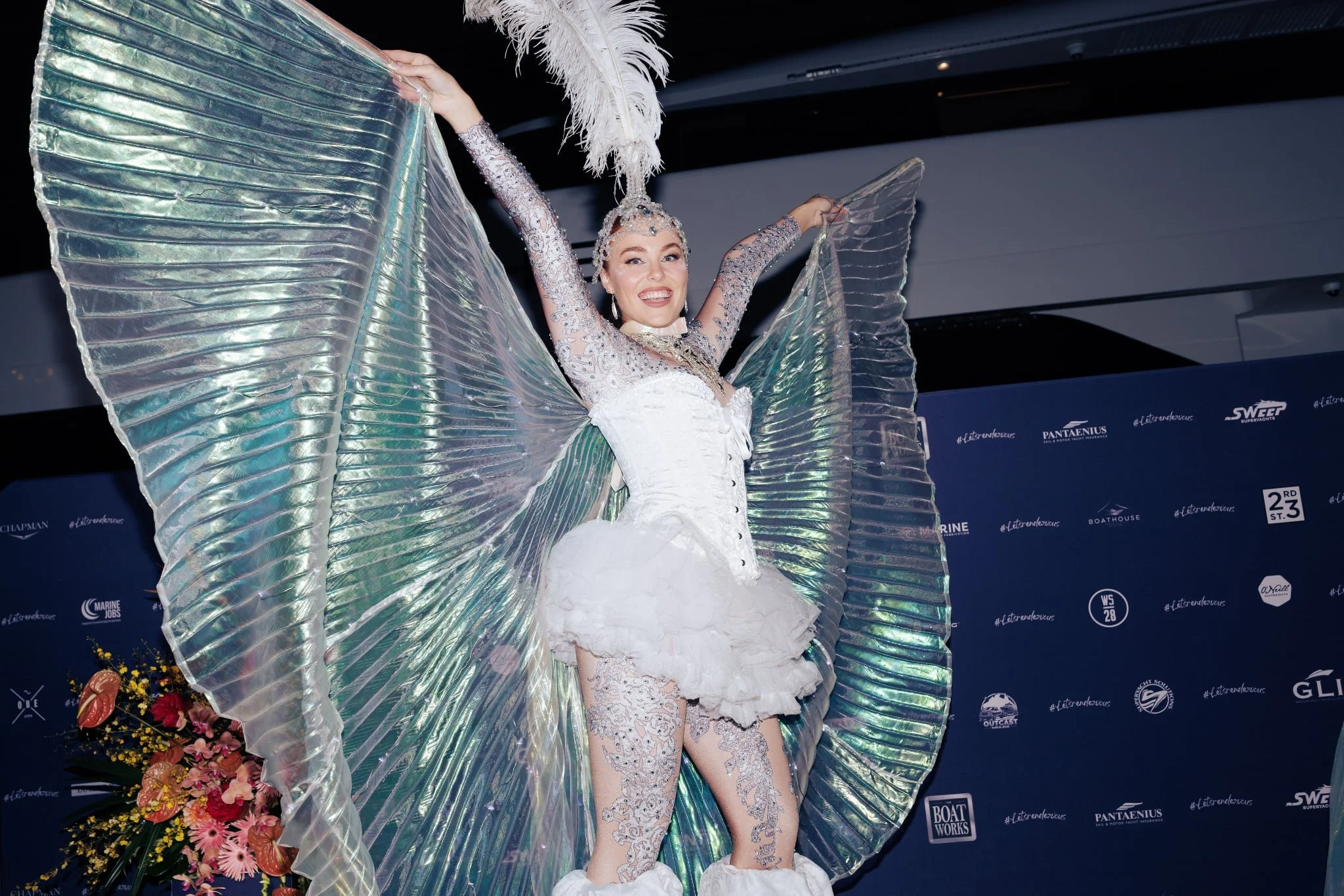 Glowing angel stilt walker with illuminated wings and feather headpiece.