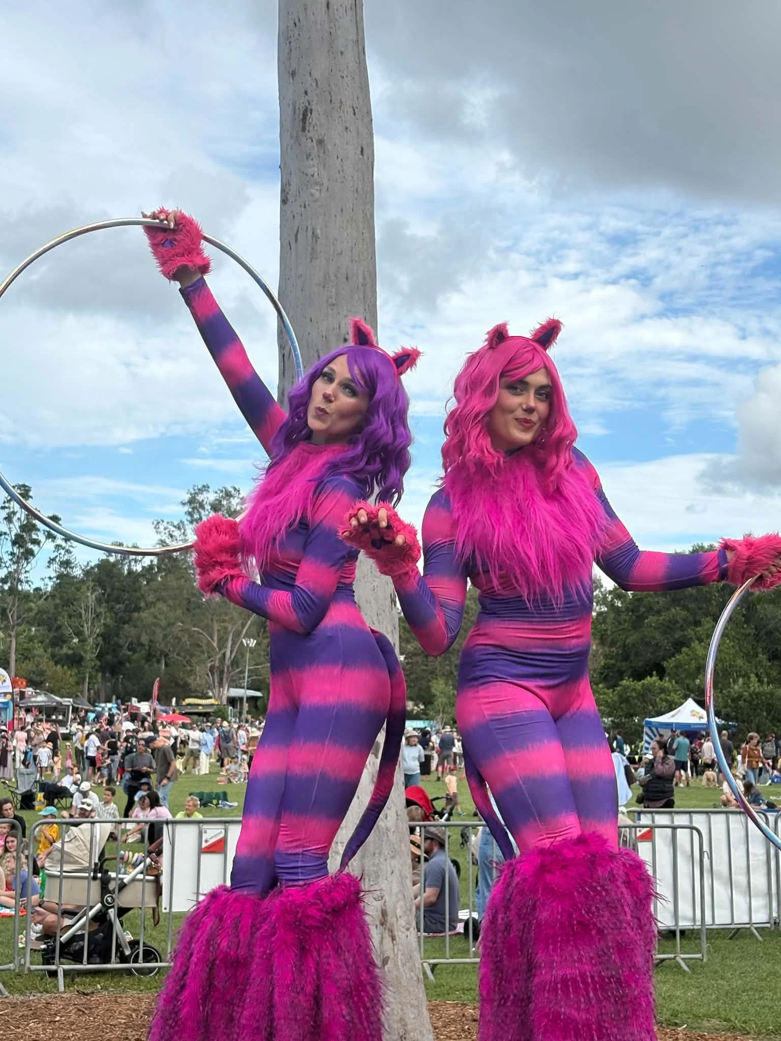 Colourful stilt walkers with large hoops creating a fun photo moment at an outdoor community festival.