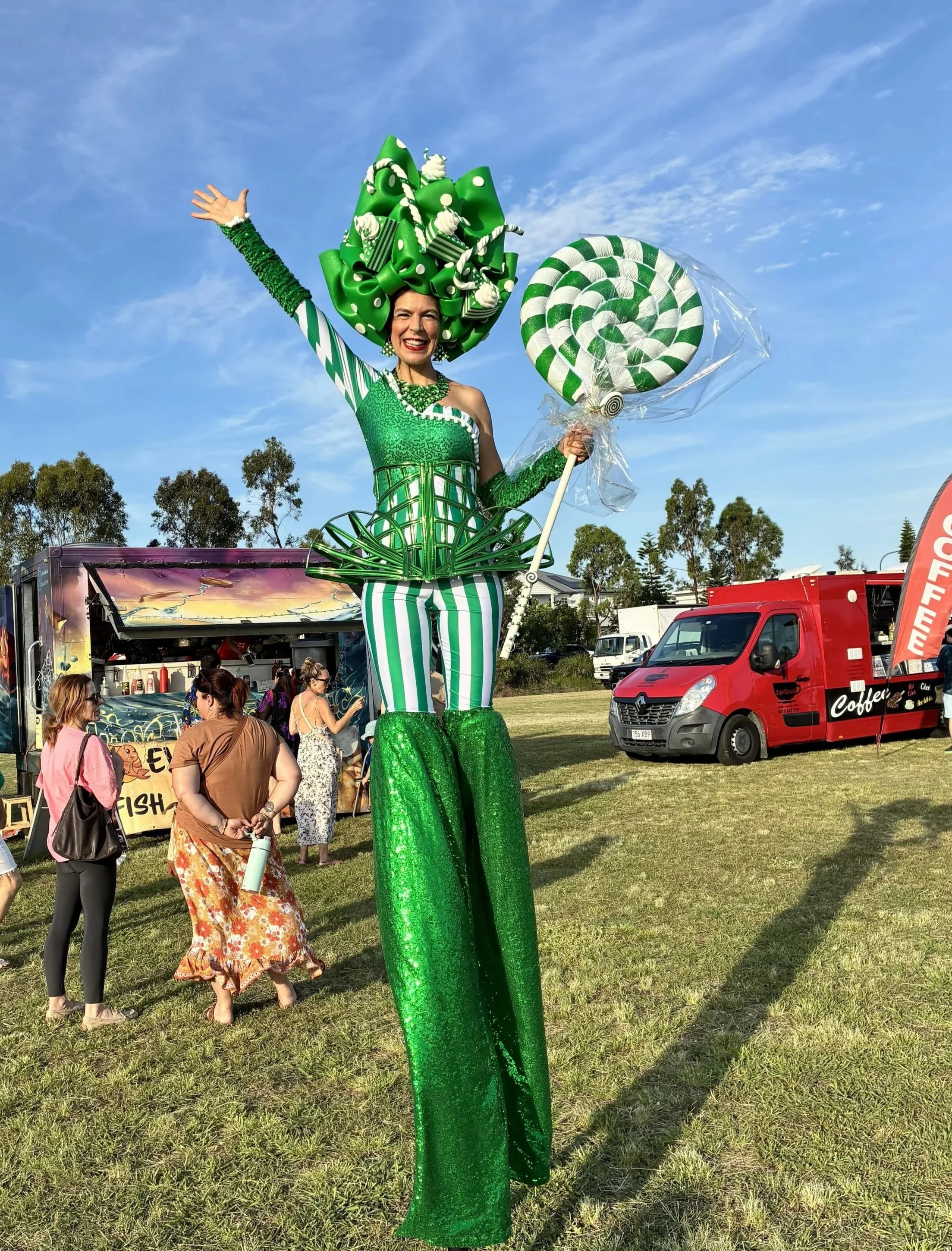 Green stilt walker performing at an outdoor family festival in Brisbane.