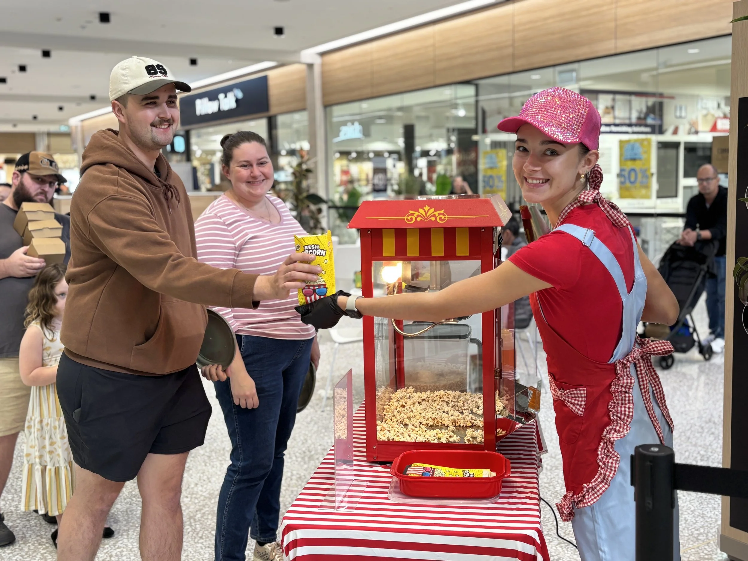 Popcorn stall with colourful setup and operator ready for customers at indoor activation