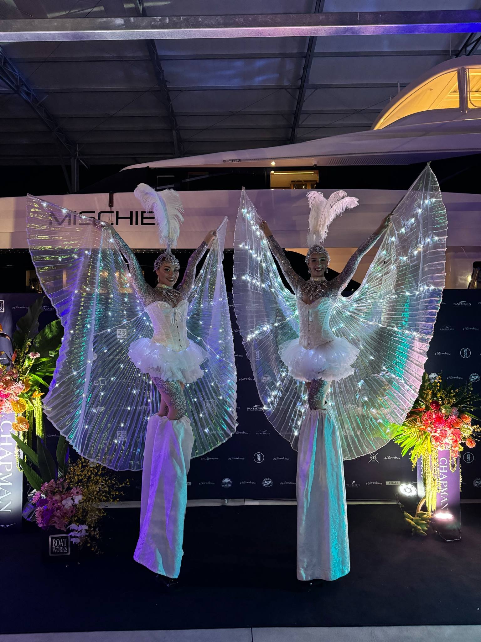 Illuminated white stilt walker with glowing wings for corporate events.