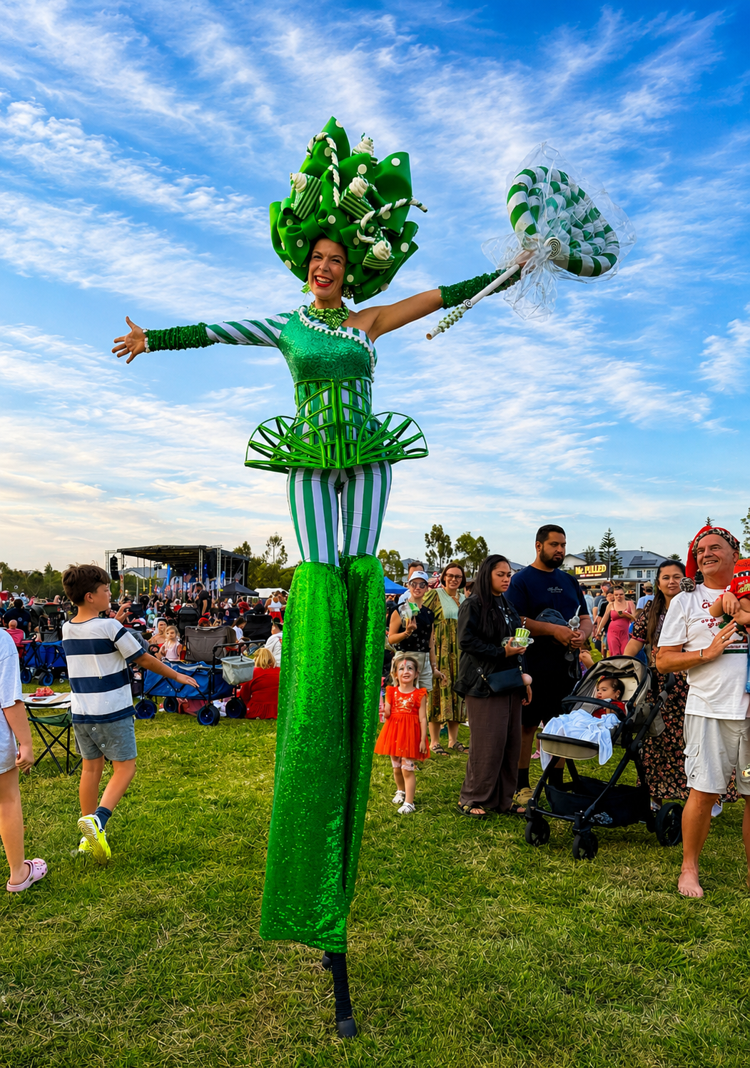 Candy-themed roving stilt performer entertaining crowds at a community event.