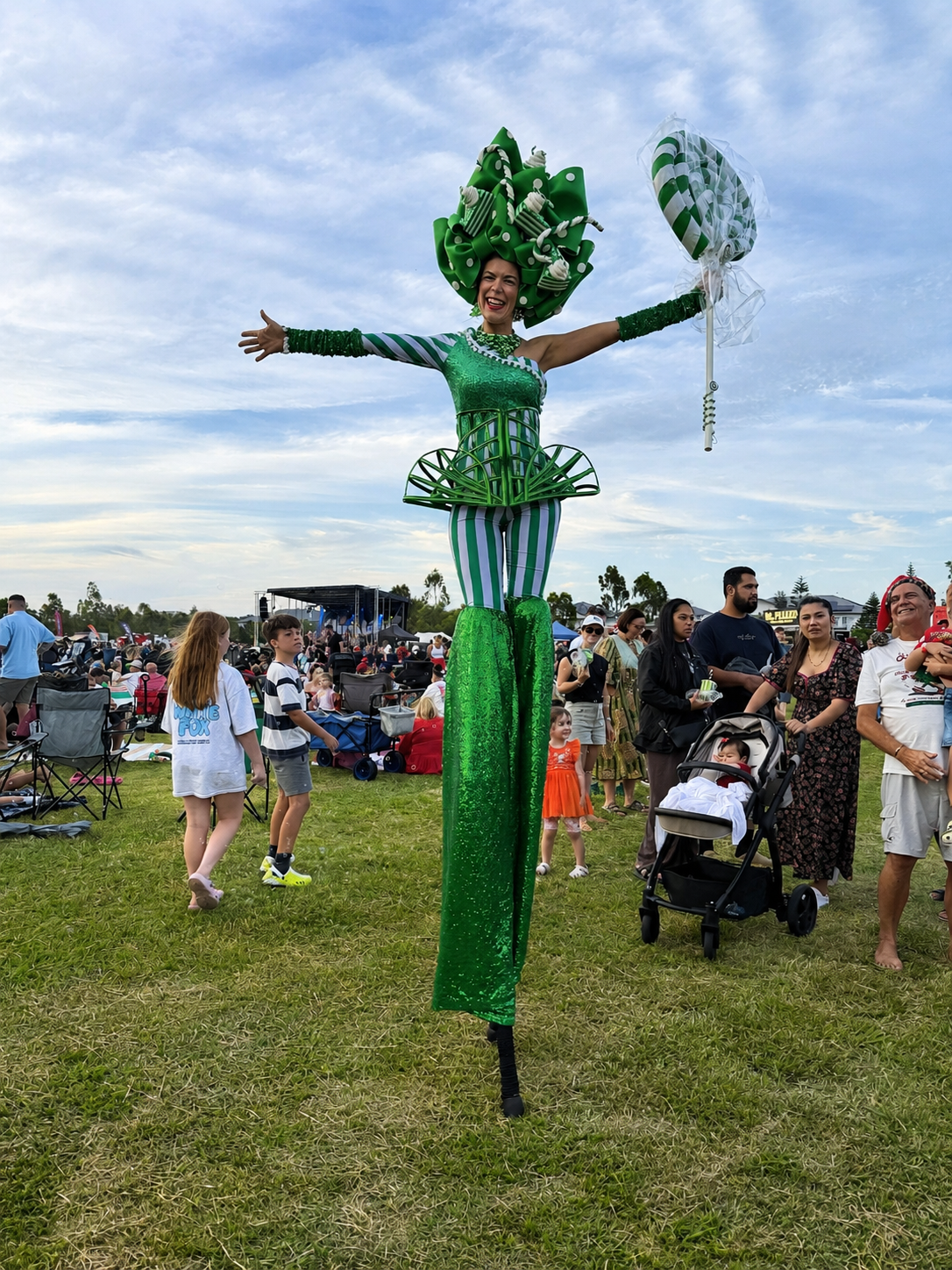 Tall roving stilt performer interacting with families at a Queensland festival.