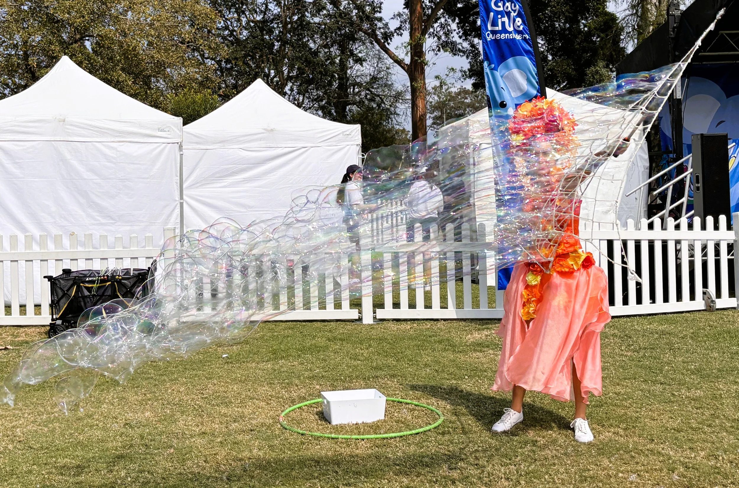 Child creating giant bubbles using large bubble wand at outdoor event