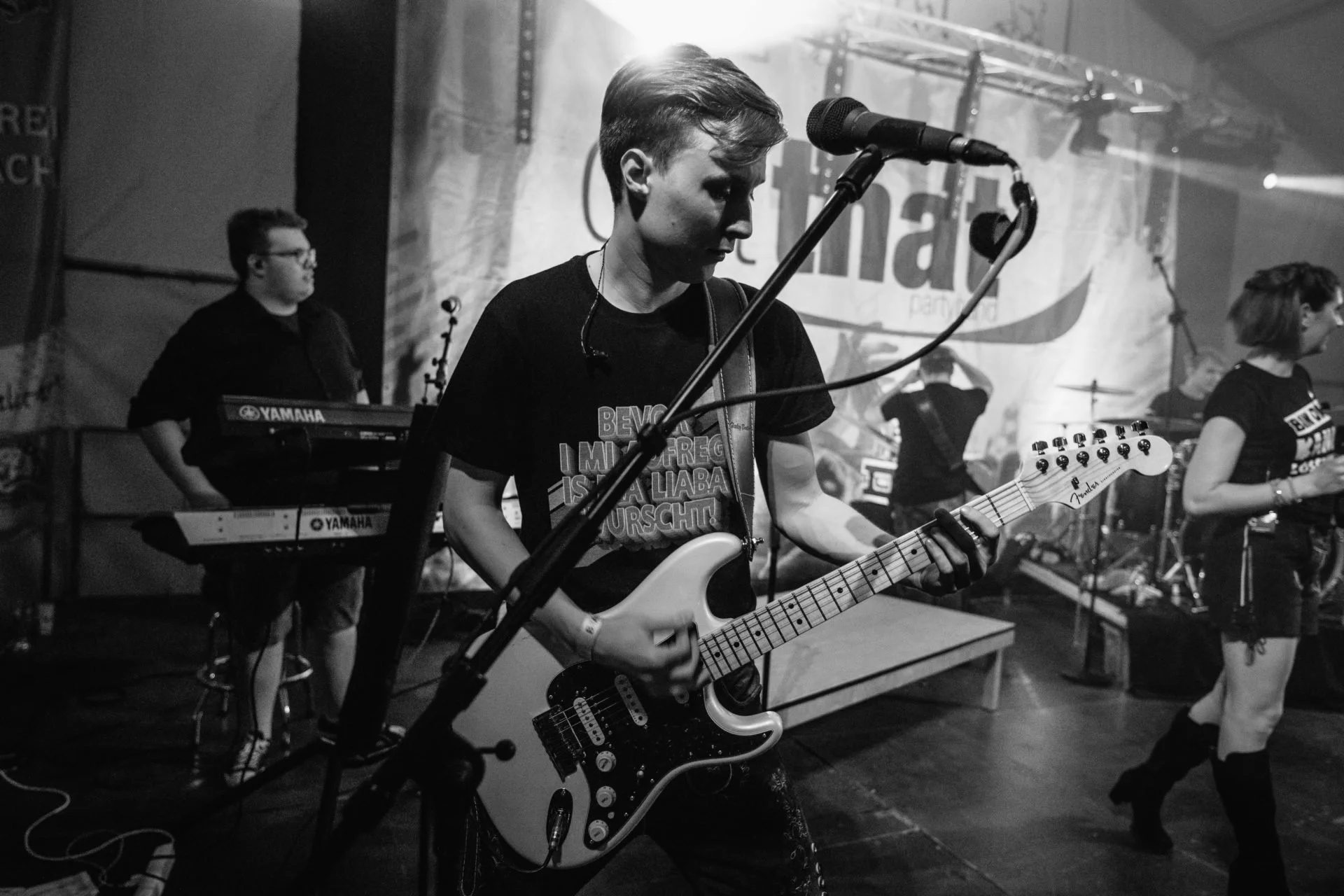 Junge Frau mit Gitarre auf einer Bühne während eines Konzerts